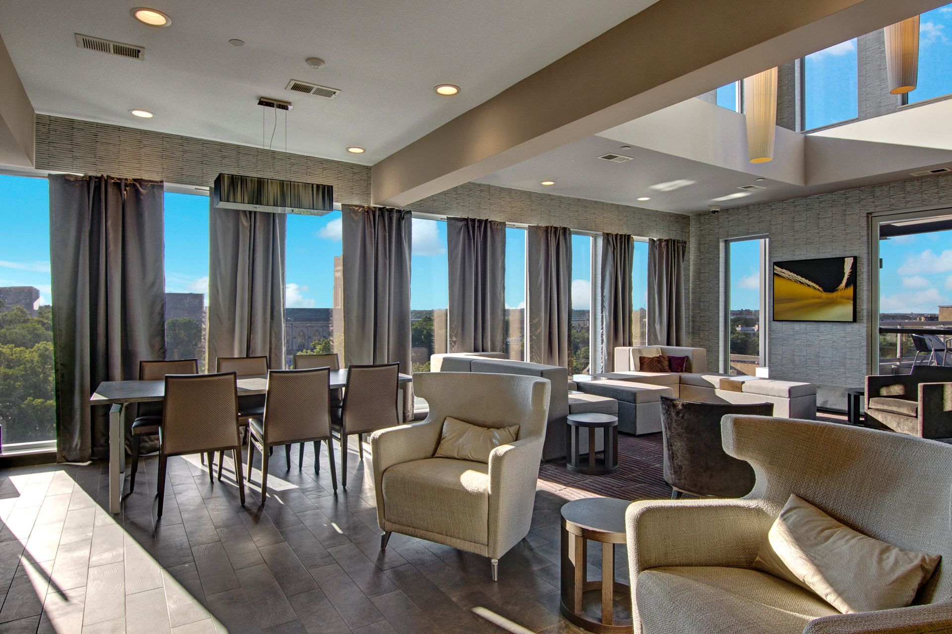 Modern lounge with chairs, tables, floor-to-ceiling windows, and mountain views
