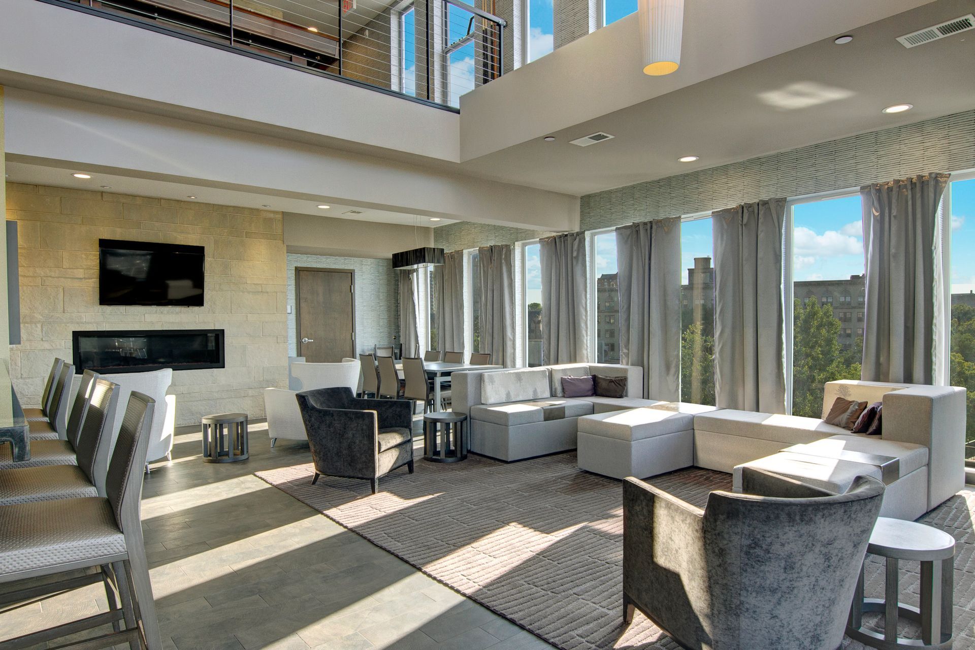 Bright modern living room with large windows, sectional sofa, fireplace, and mounted TV