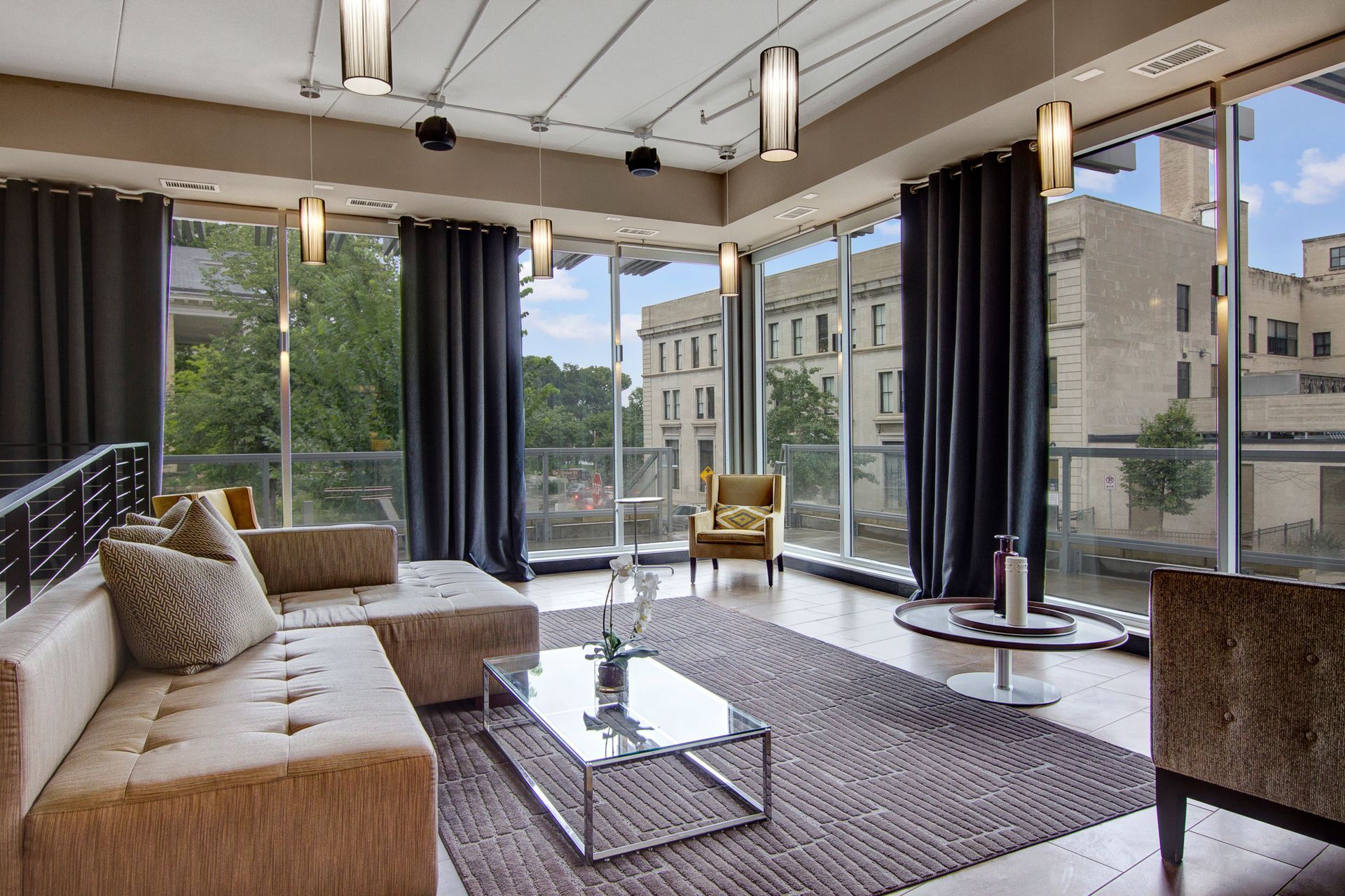 Modern living room with floor-to-ceiling windows, beige sofa, and city views