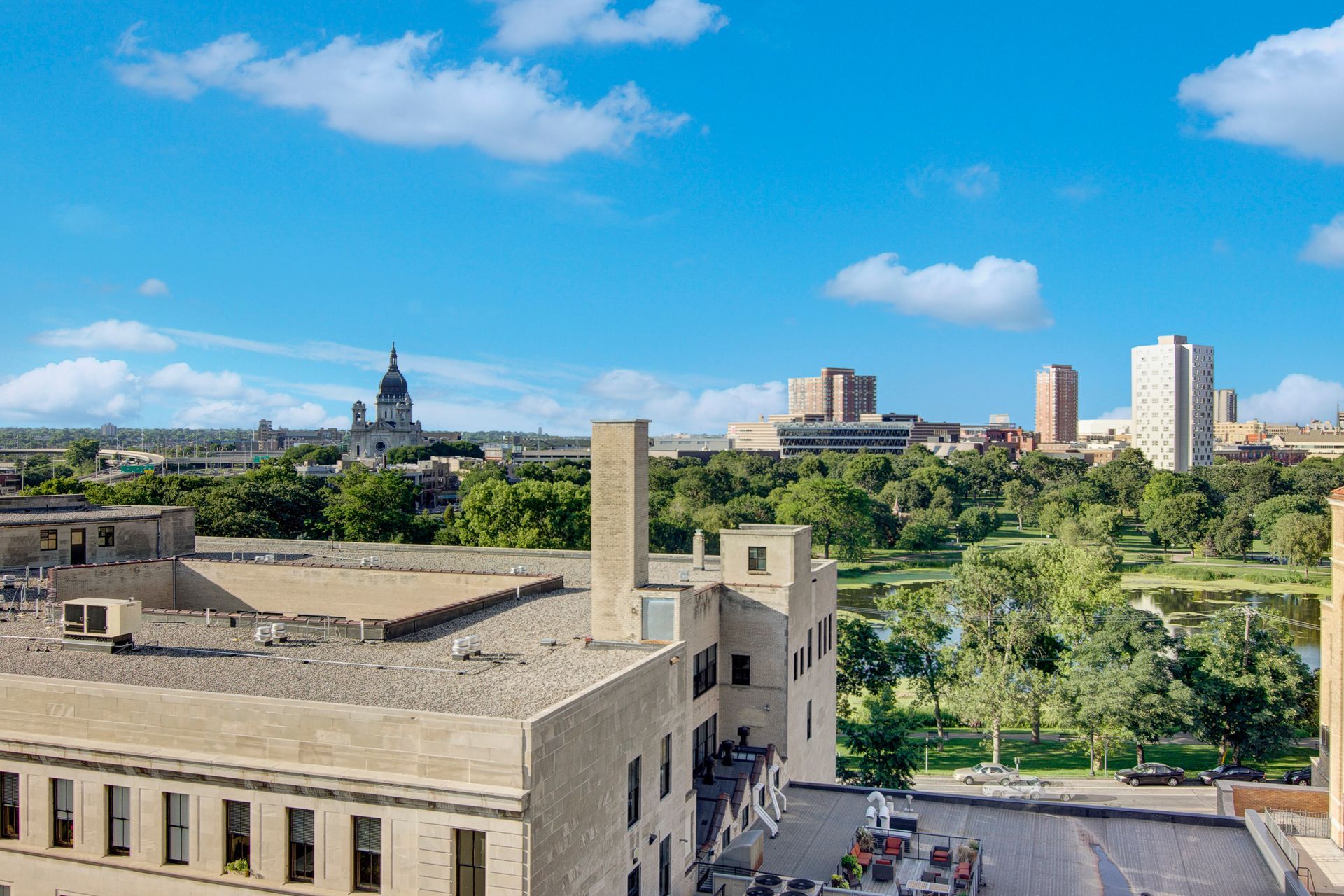 City skyline with historic building, green park, and blue sky with clouds