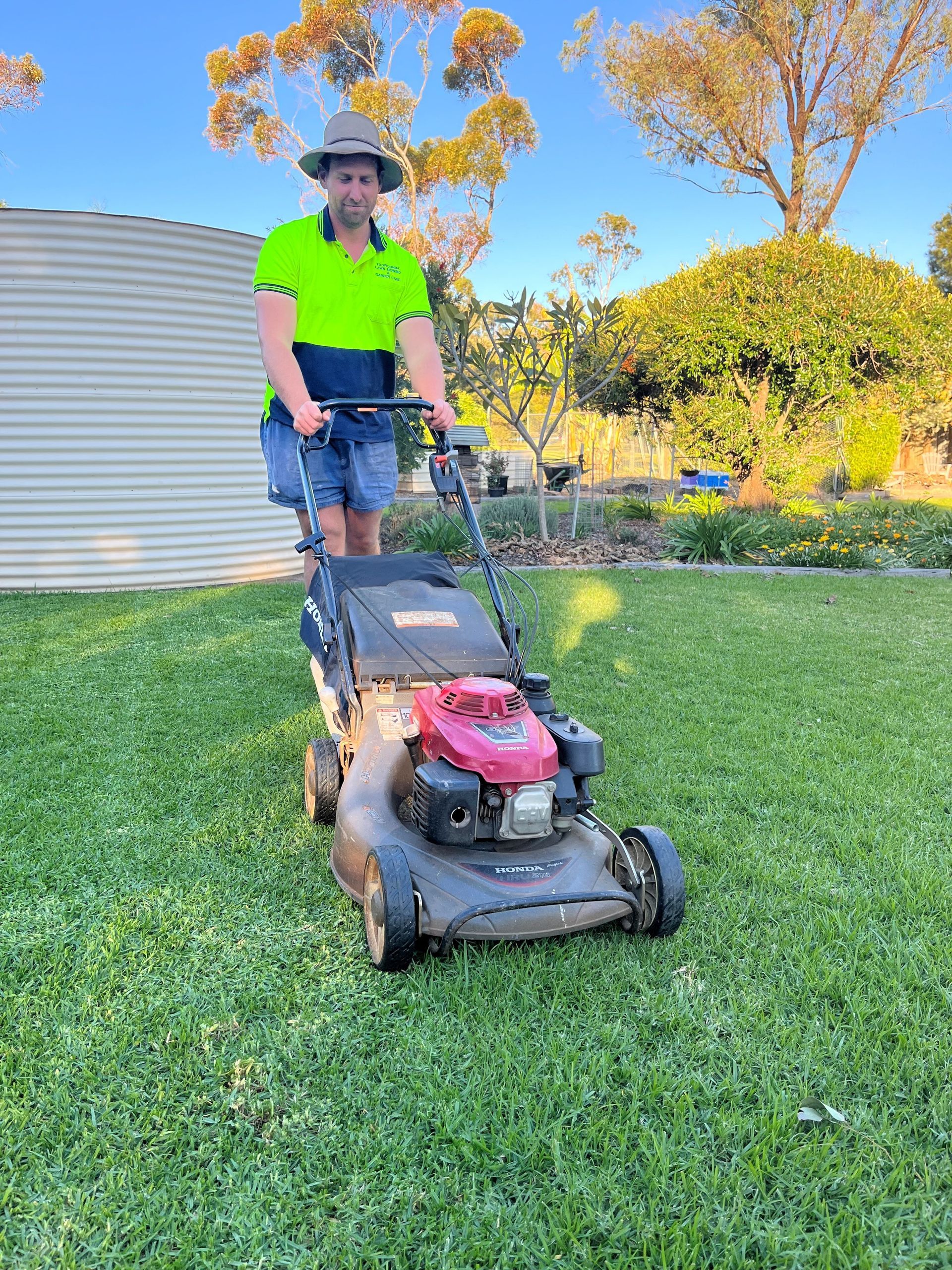 A man is cutting the grass with a lawn mower.