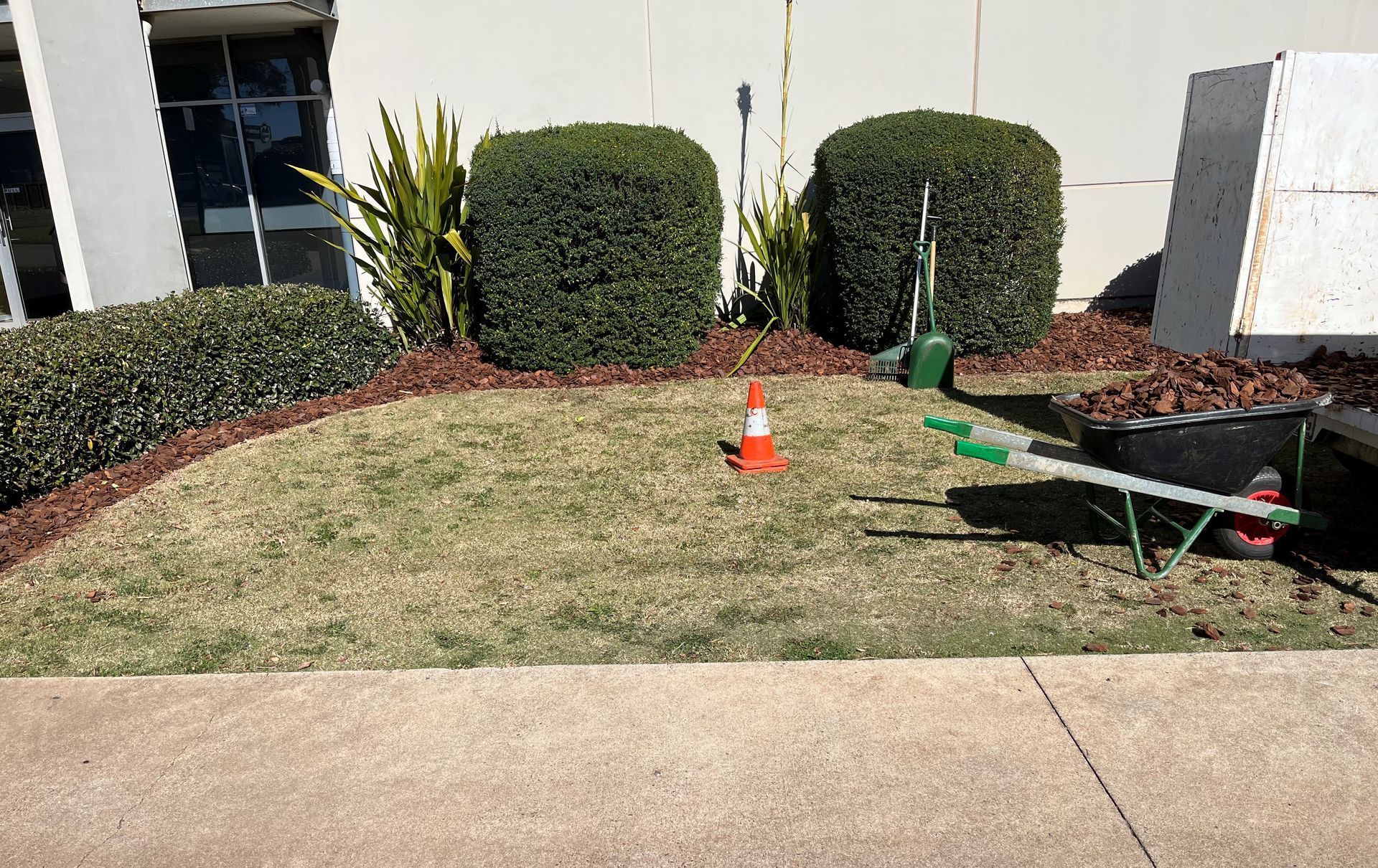 A wheelbarrow is parked in the grass in front of a building.