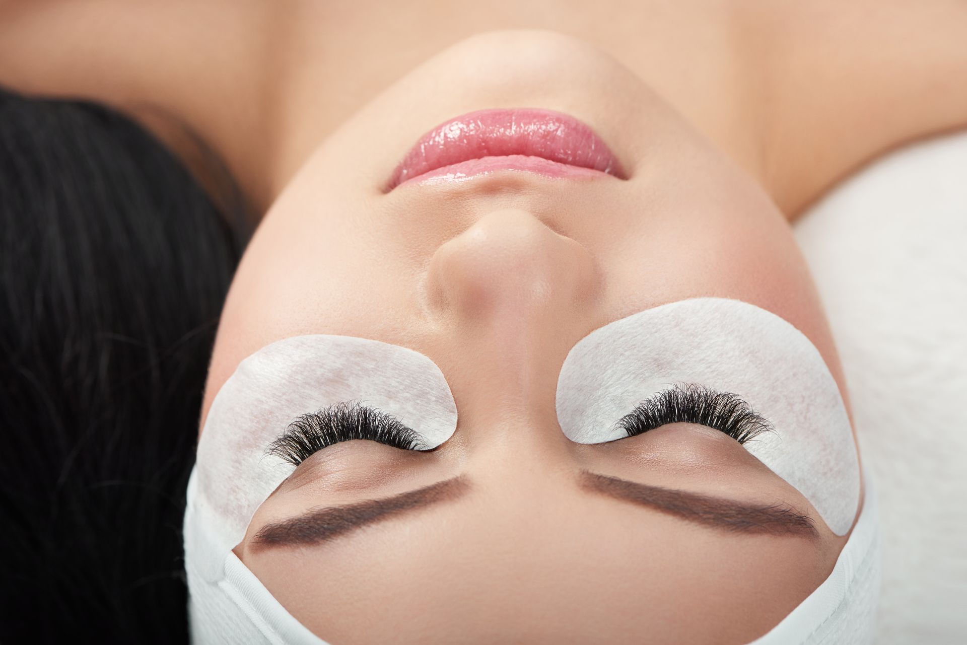 A woman is getting eyelash extensions in a beauty salon.