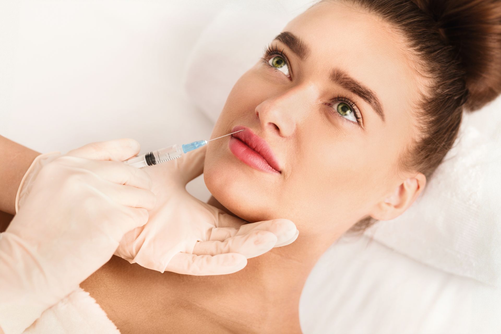 A woman is getting a botox injection in her lips.