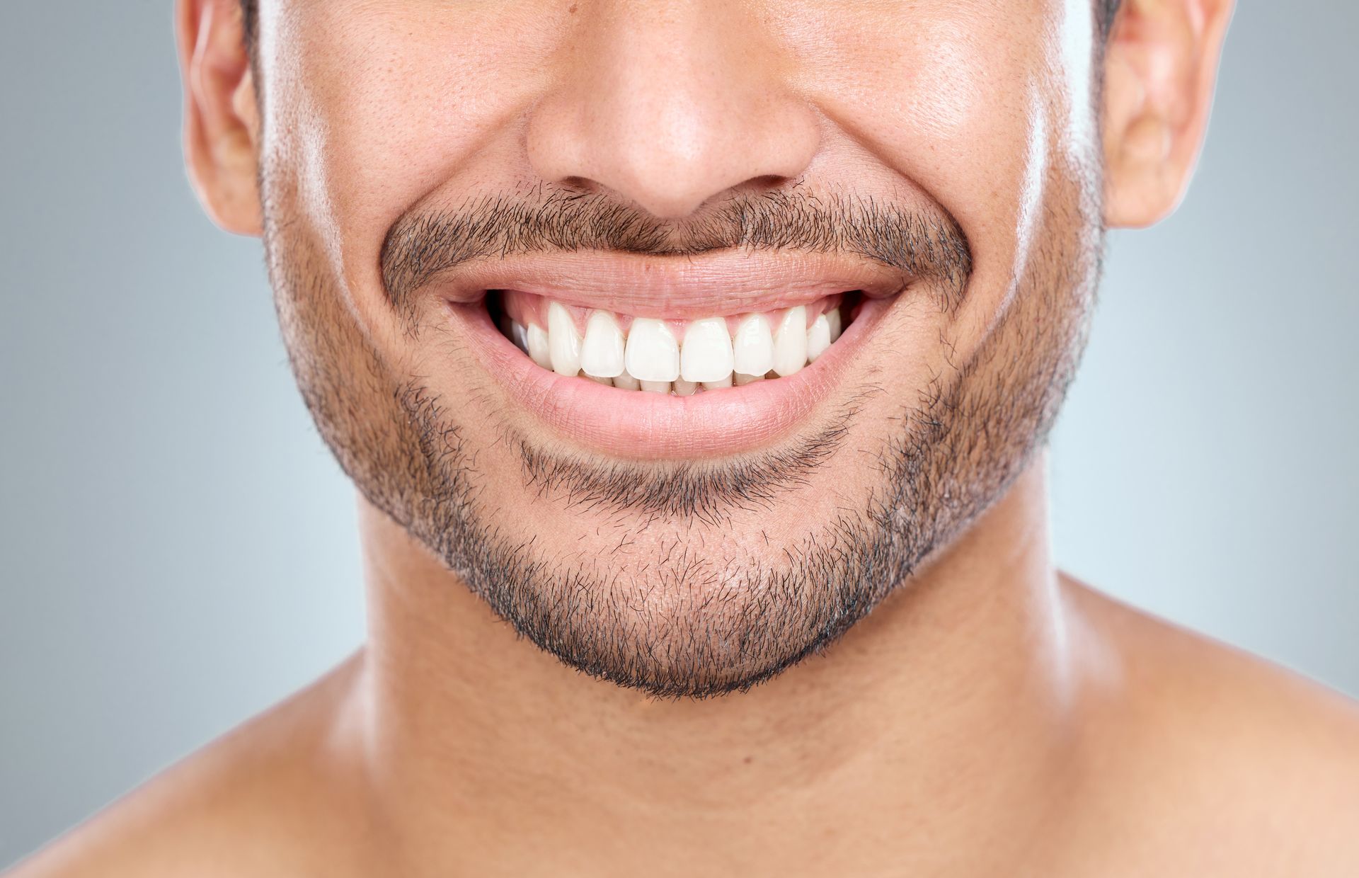 A close up of a man 's face with a beard smiling.