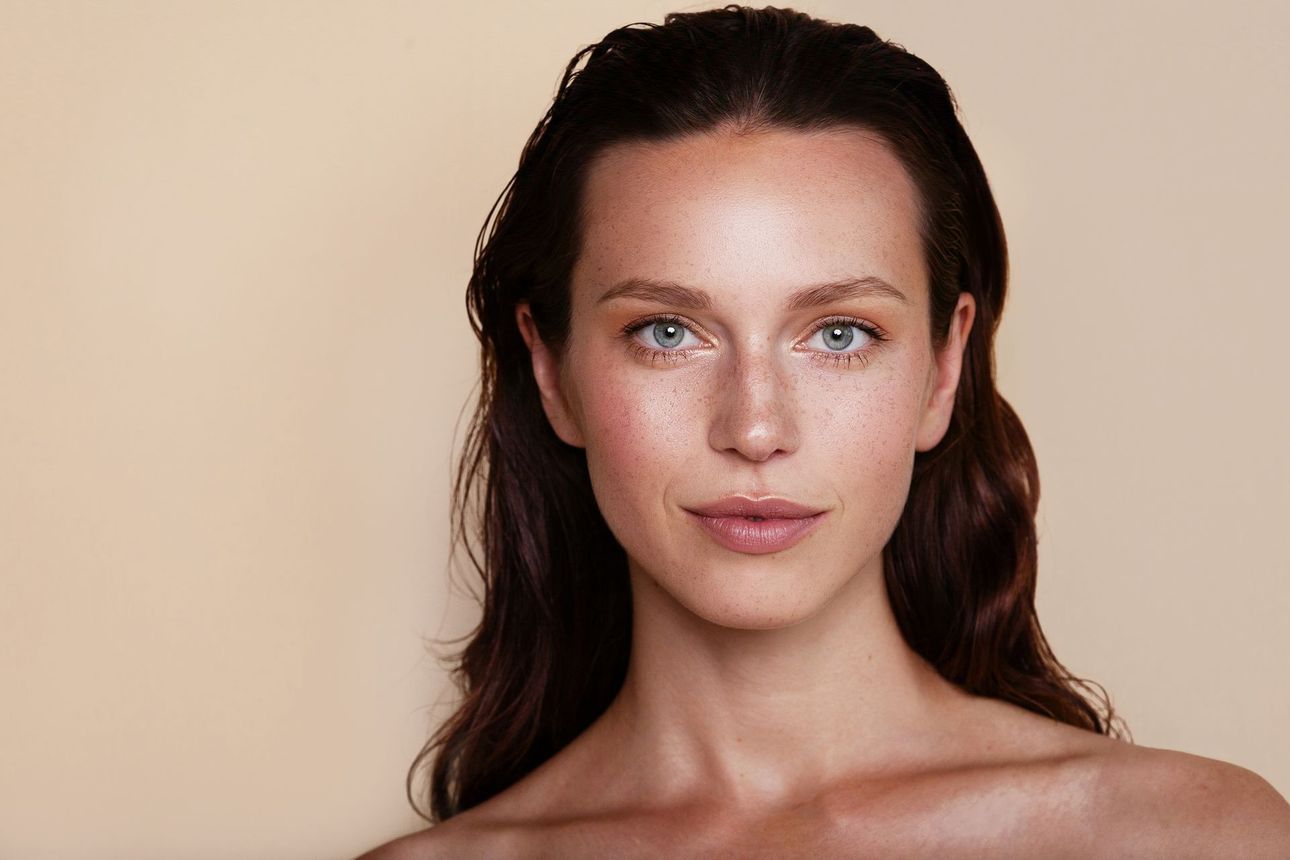 A close up of a woman 's face on a beige background.