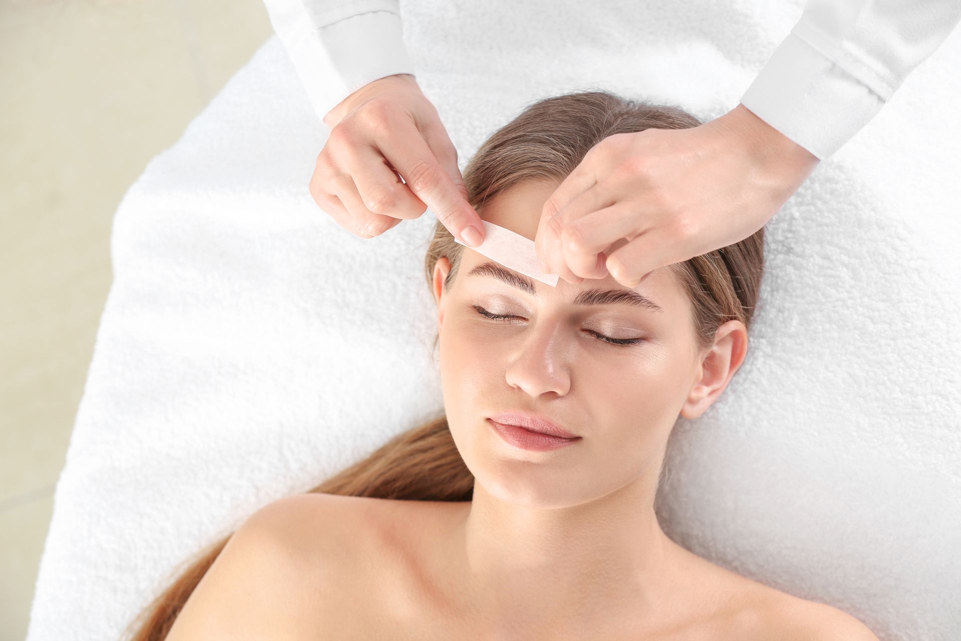 A woman is getting her eyebrows waxed in a beauty salon.