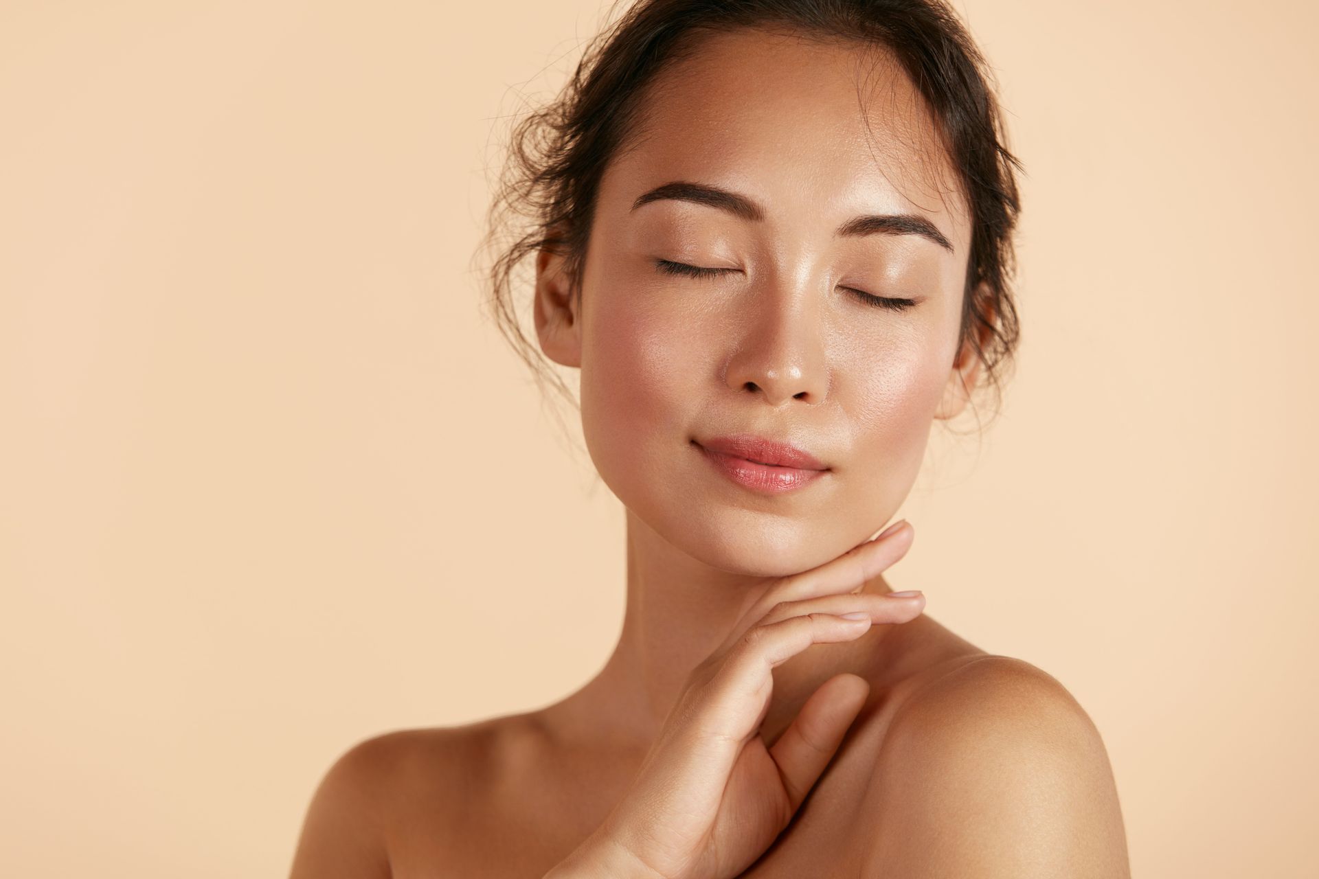 A woman with her eyes closed is touching her face with her hand.