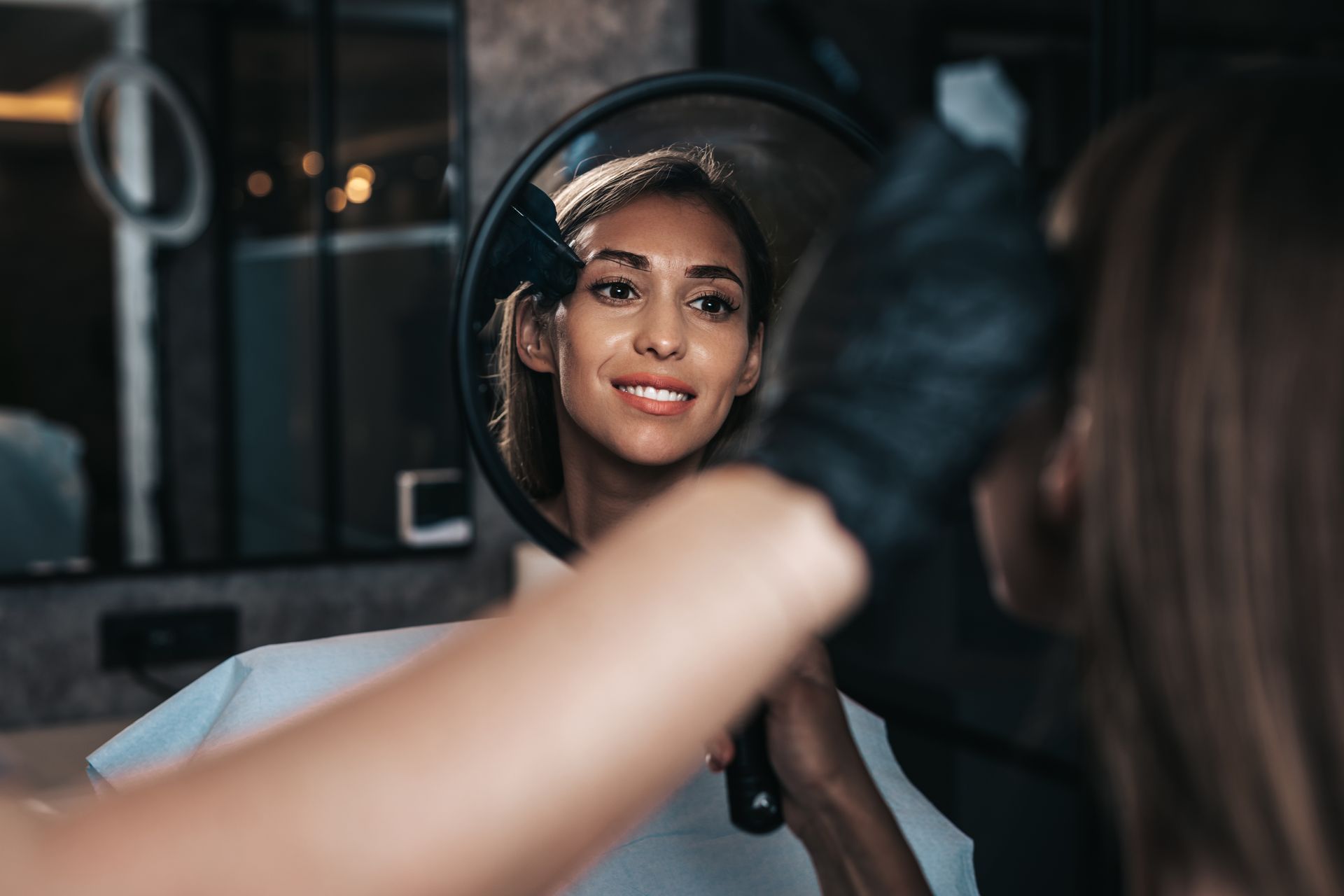 A woman is looking at her reflection in a mirror.