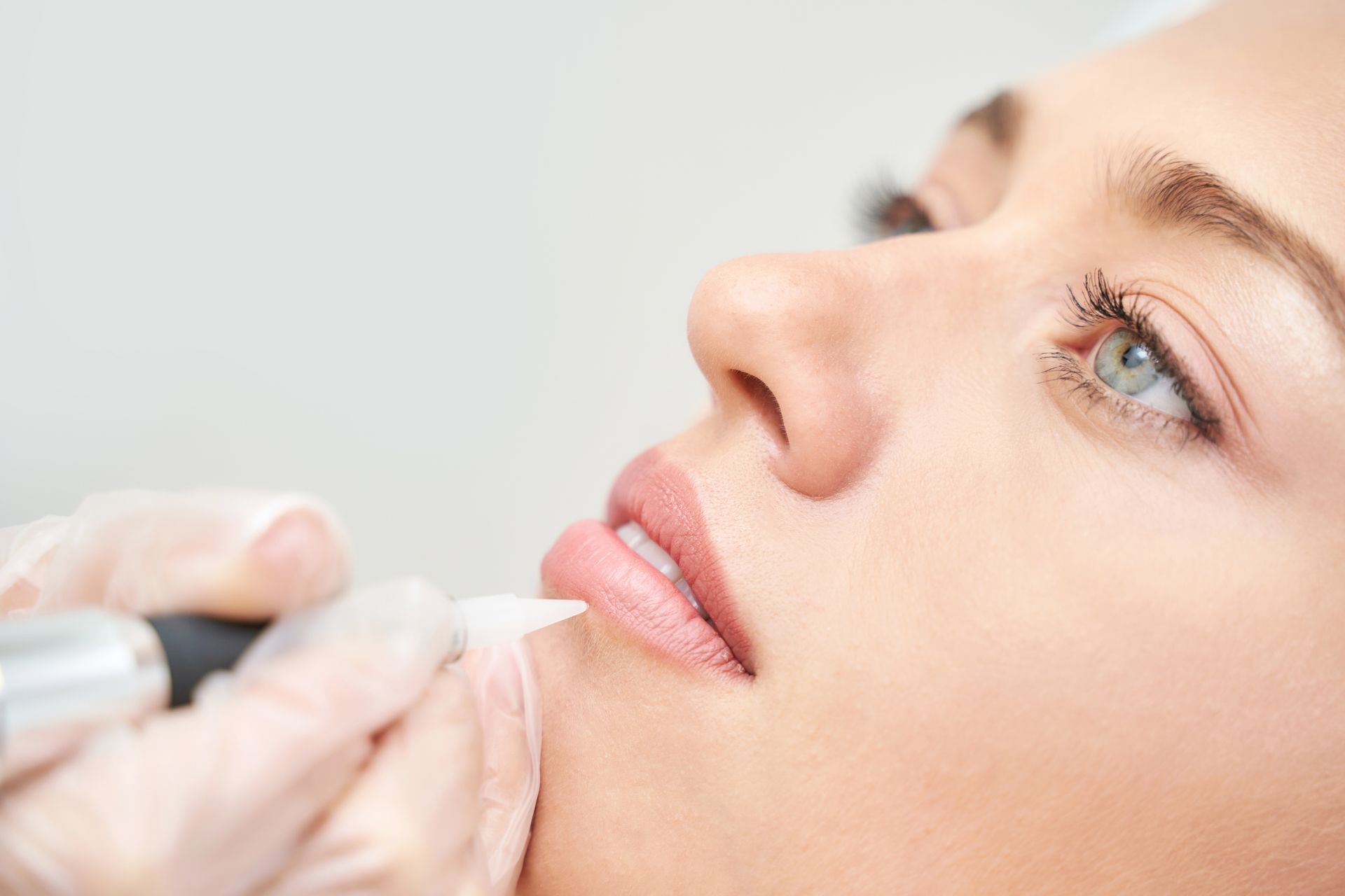 A woman is getting a permanent lip tattoo on her lips.