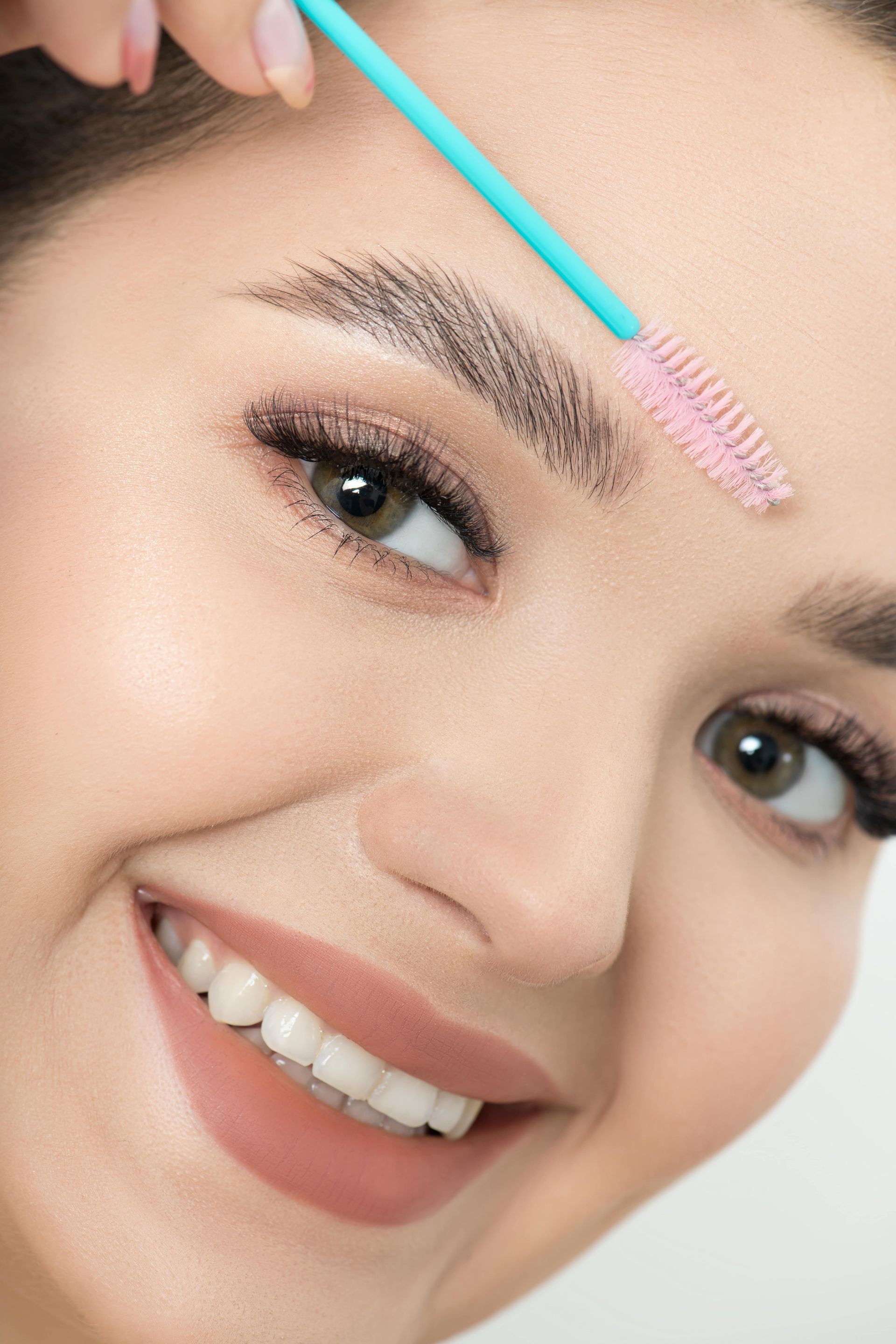 A woman is brushing her eyebrows with a brush.