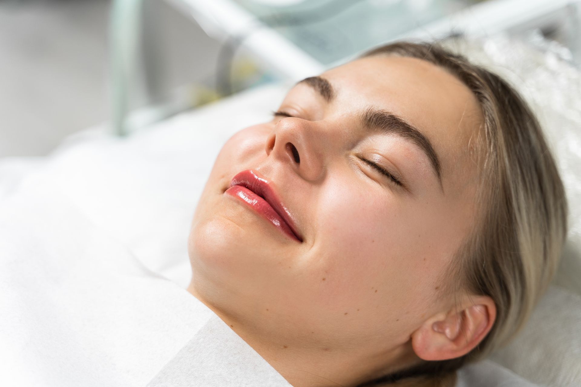 A woman is laying on a bed with her eyes closed and smiling.