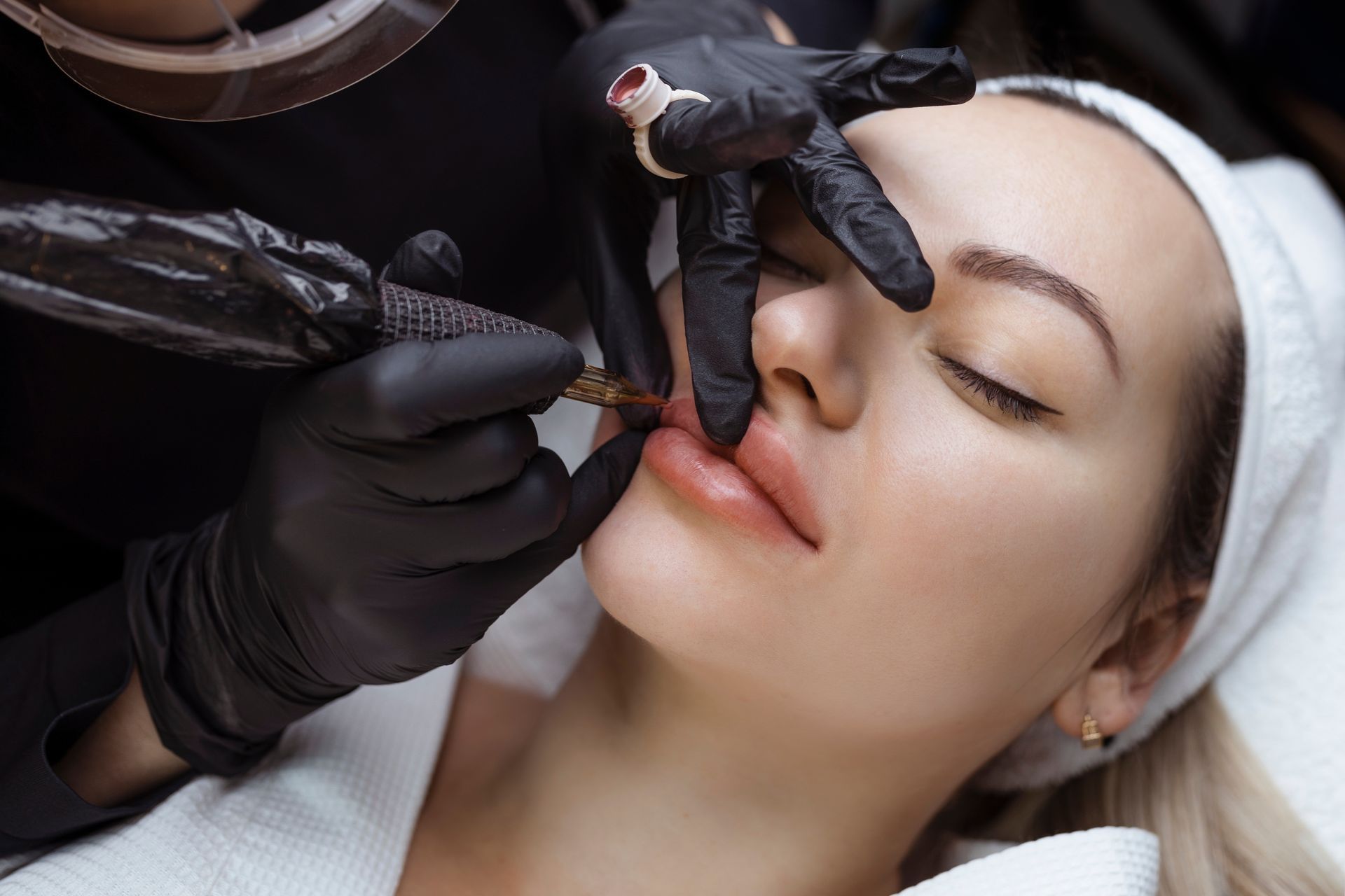 A woman is getting a tattoo on her lips.