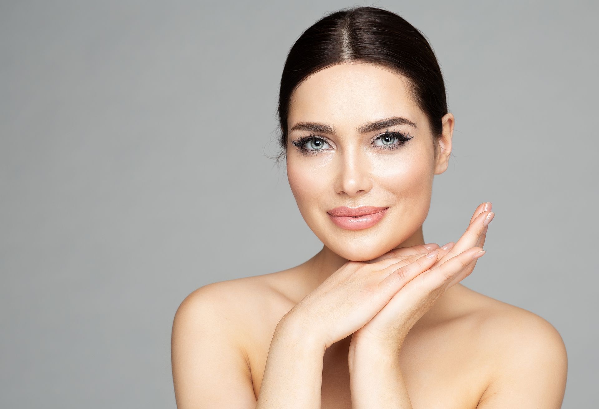 A close up of a woman 's face with her hands on her chin.