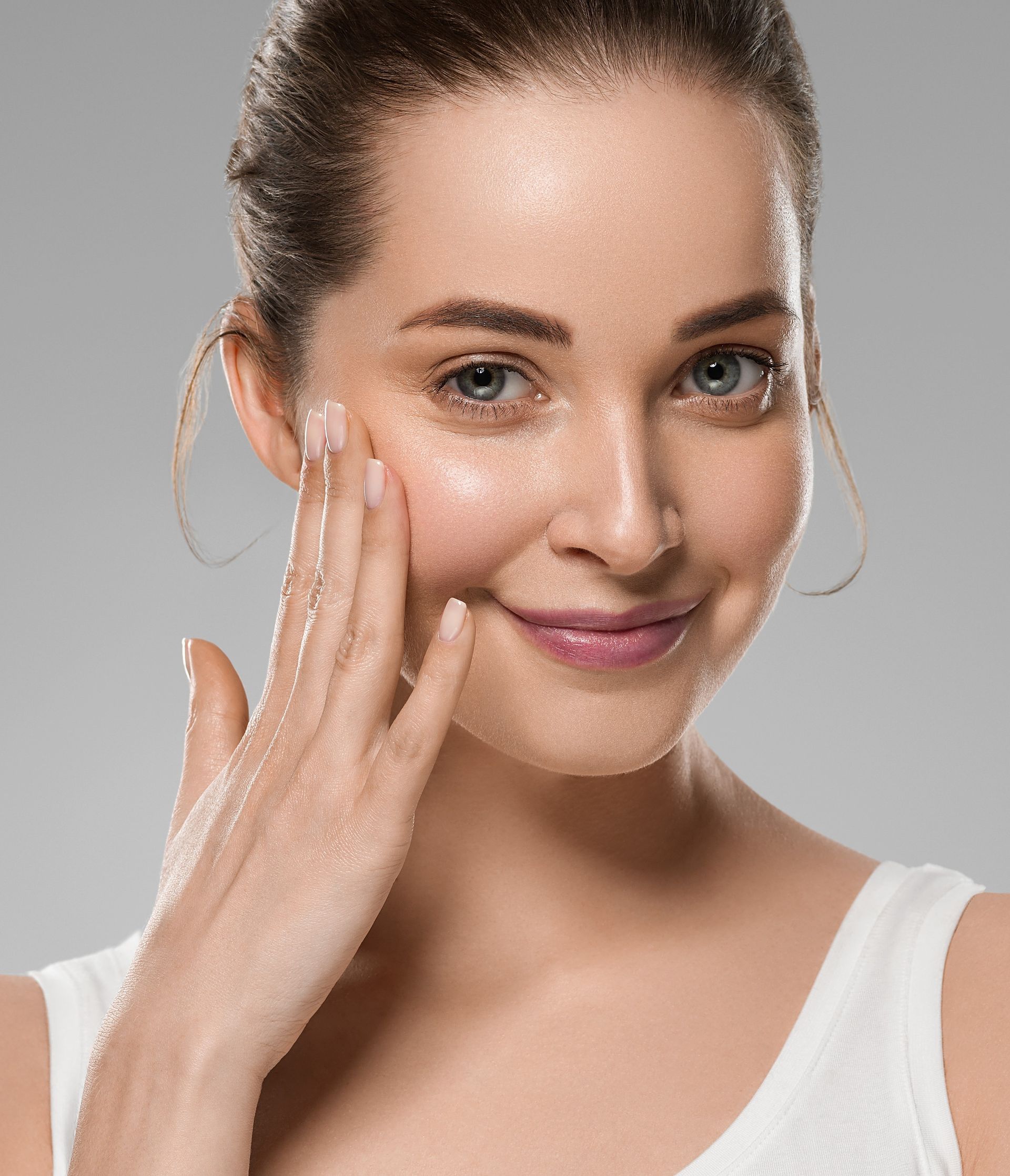 A woman is touching her face with her hand and smiling.