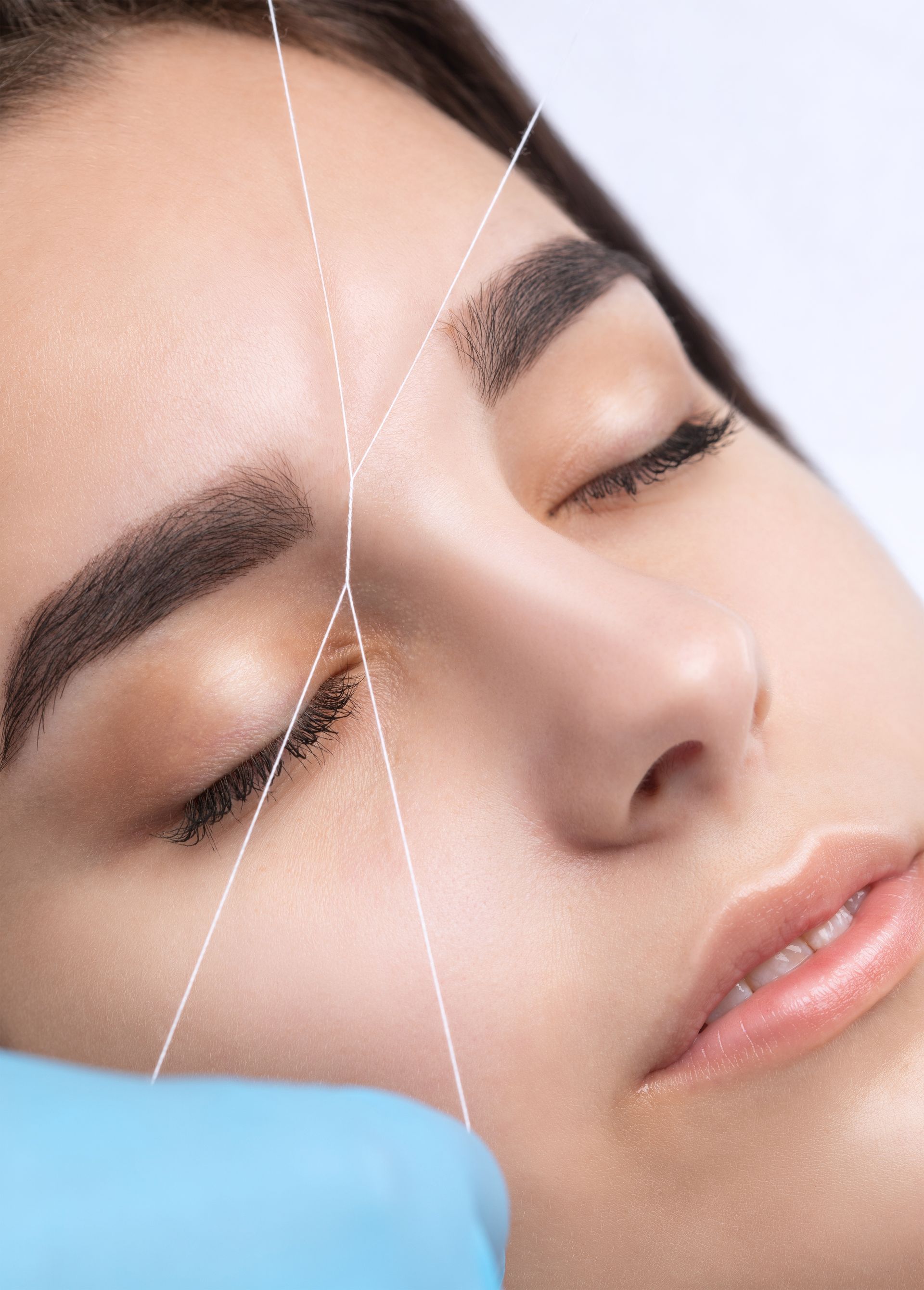 A woman is getting her eyebrows threaded in a beauty salon.