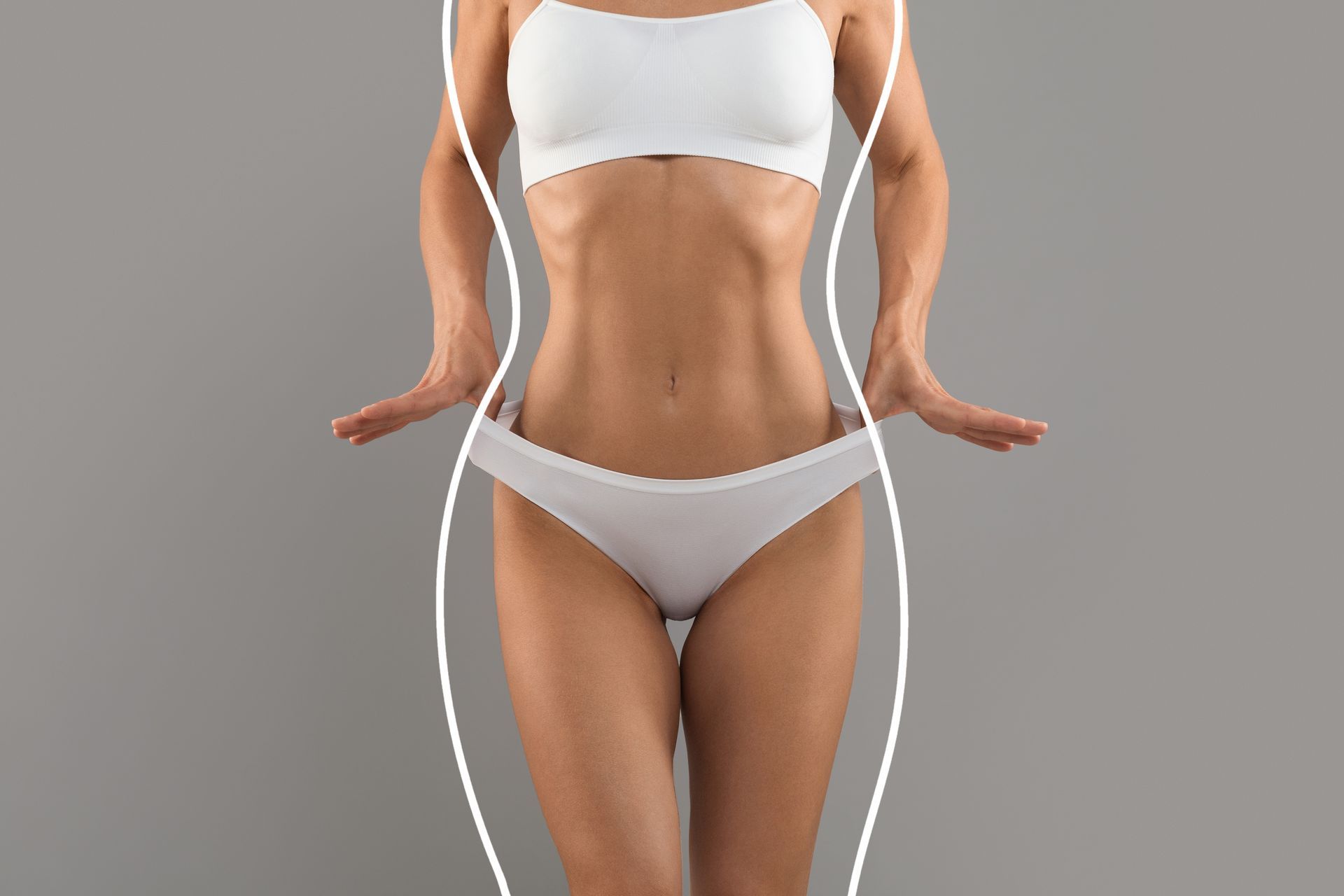 A woman in white underwear is standing in front of a gray background.