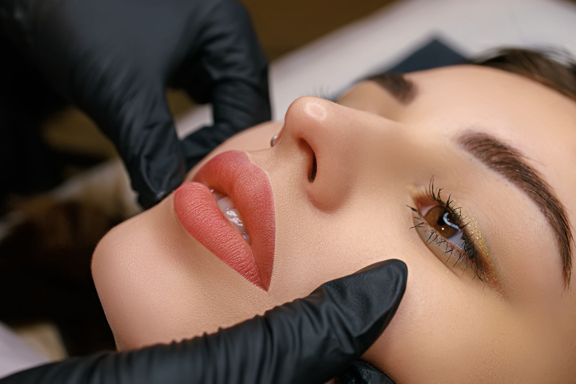 A woman is getting permanent makeup on her lips.