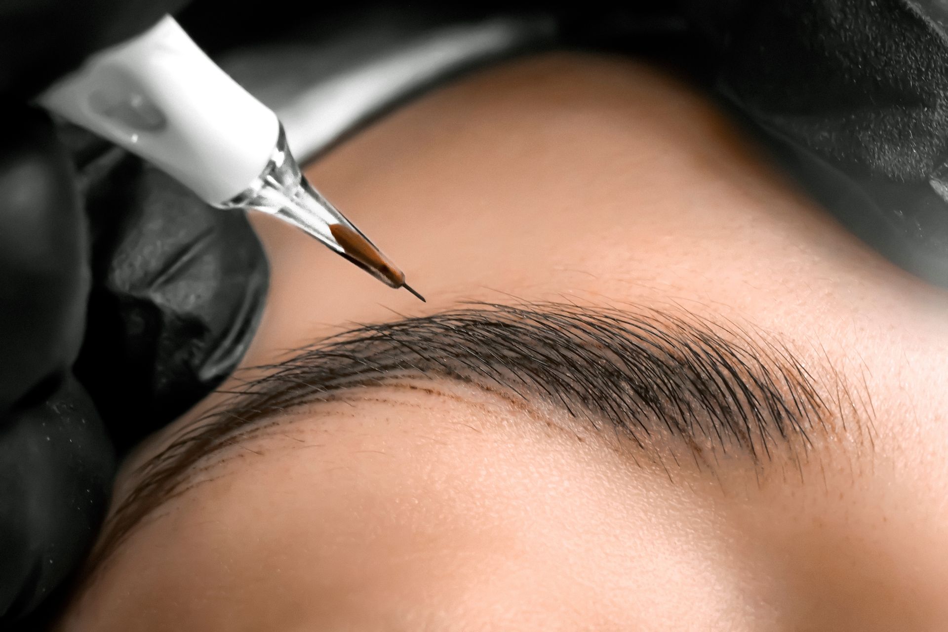 A close up of a person getting a tattoo on their eyebrows.