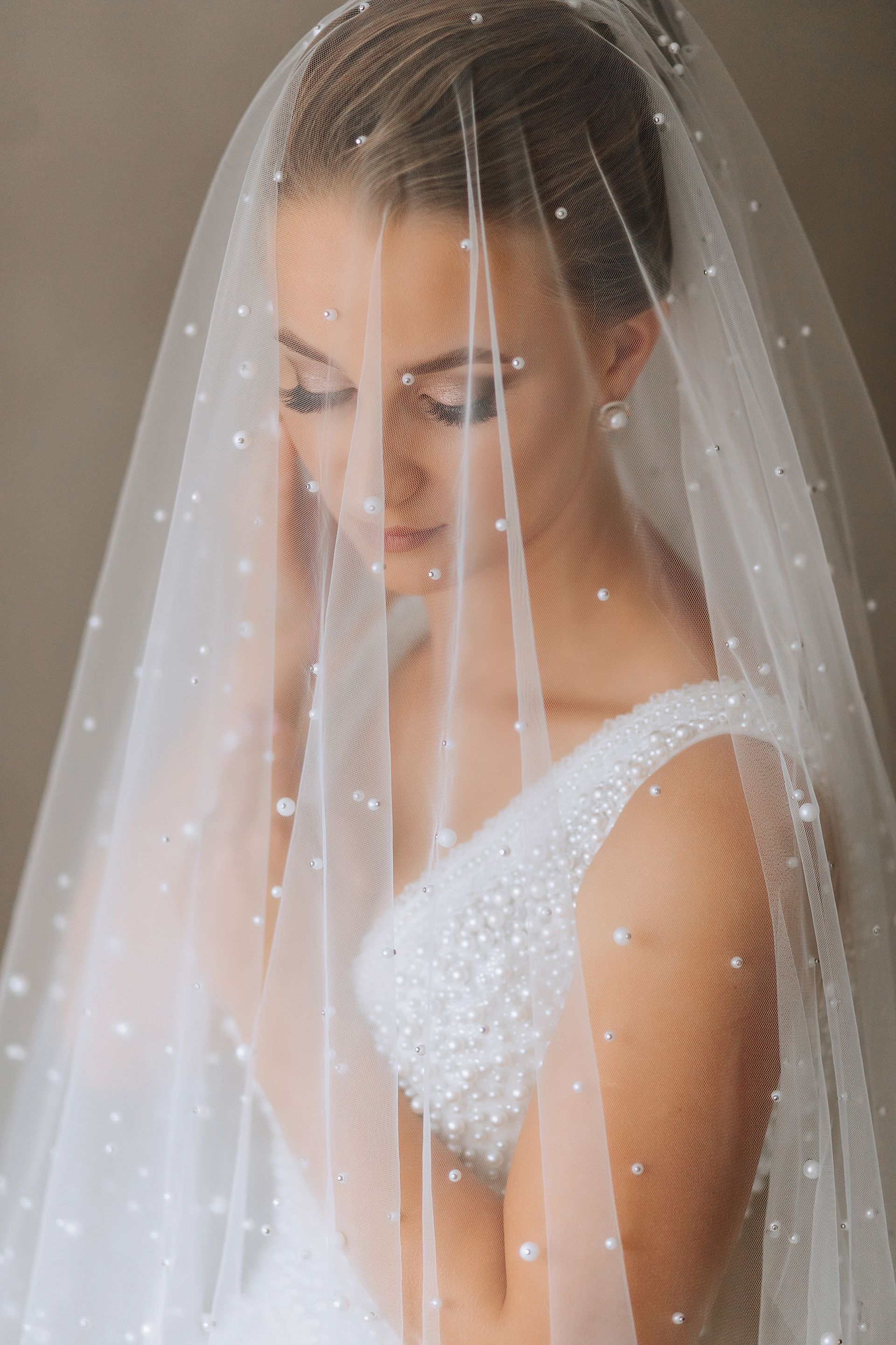 A bride in a wedding dress and veil is looking down.