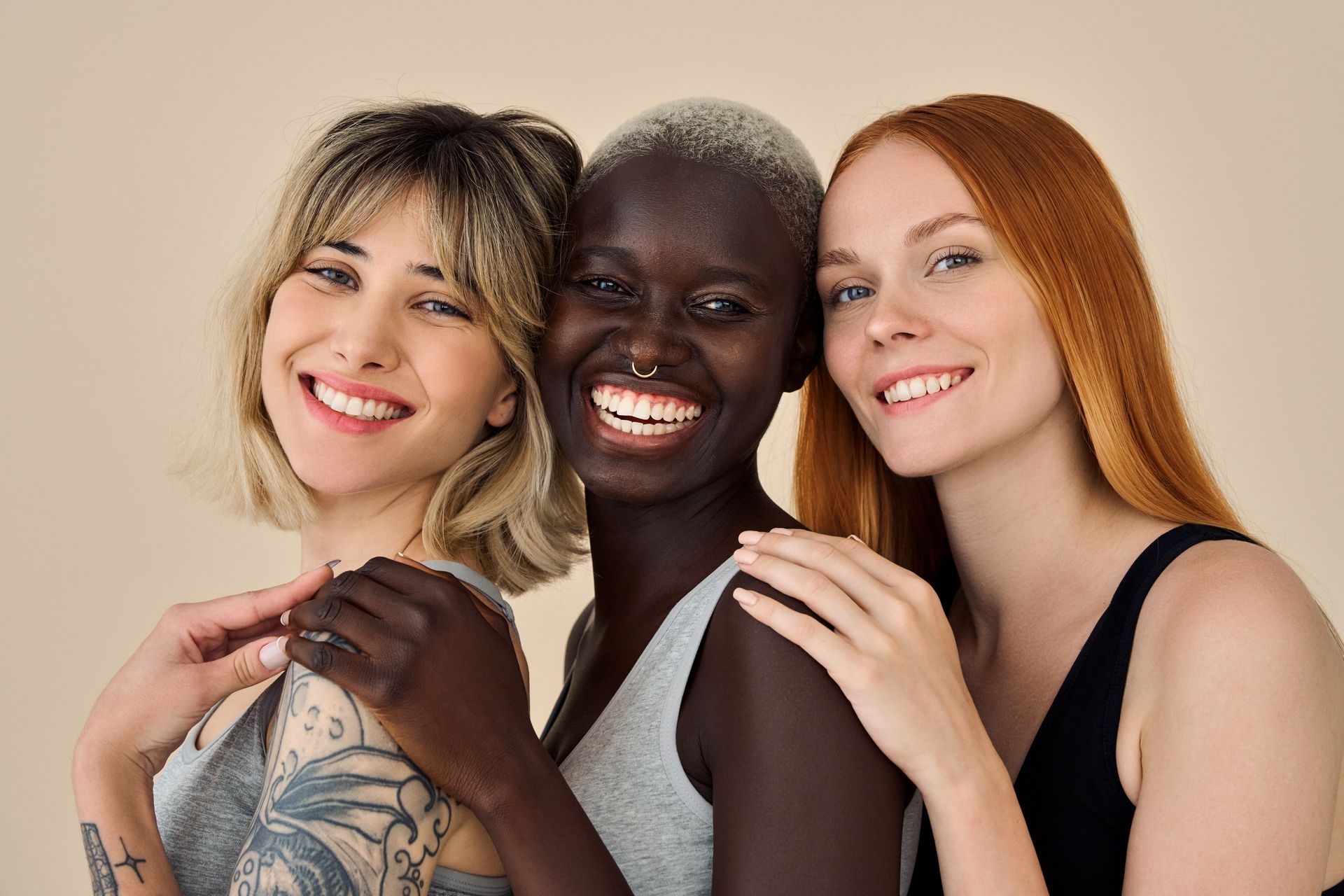 Three smiling people posing closely together against a beige background.