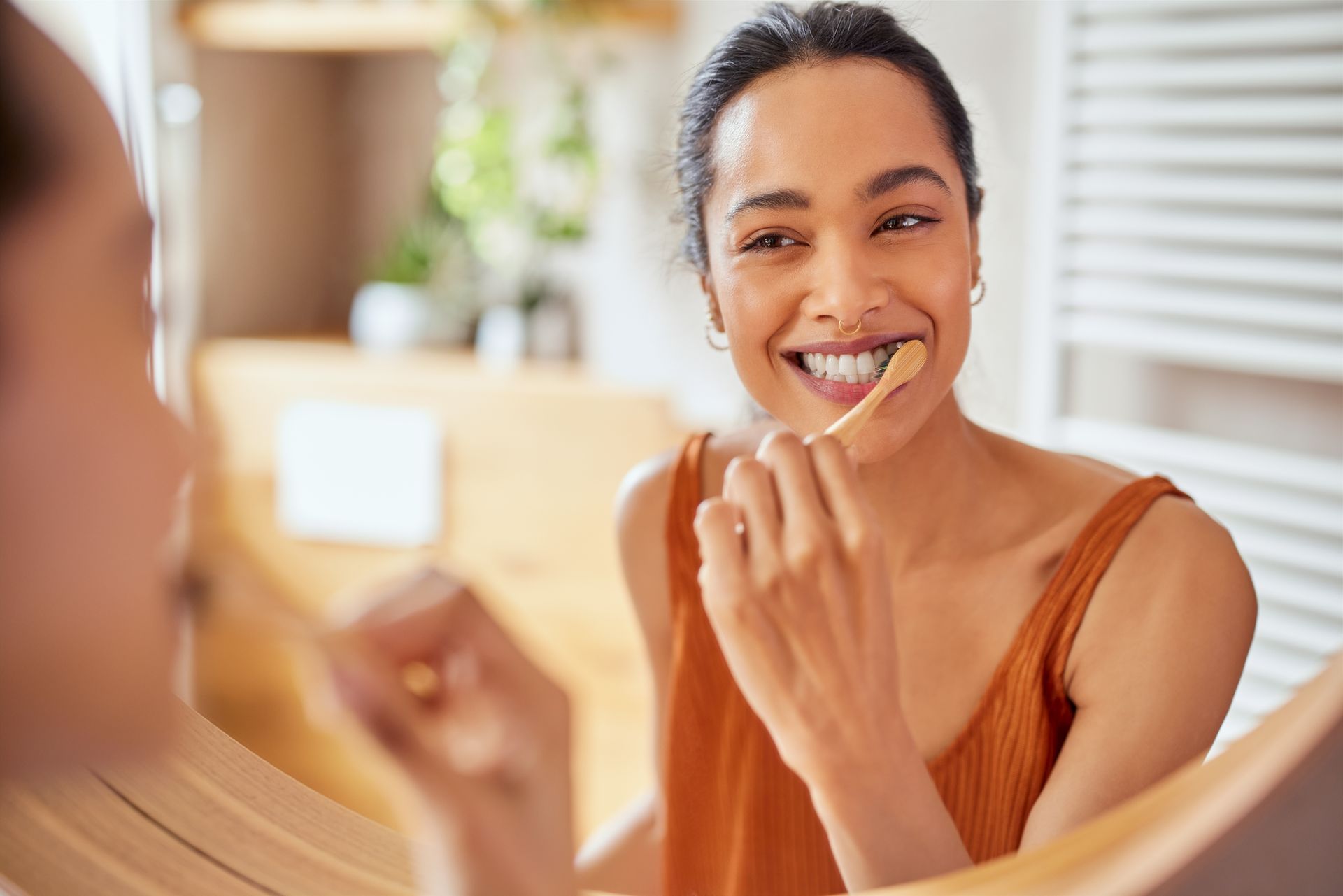 A woman is brushing her teeth in front of a mirror.