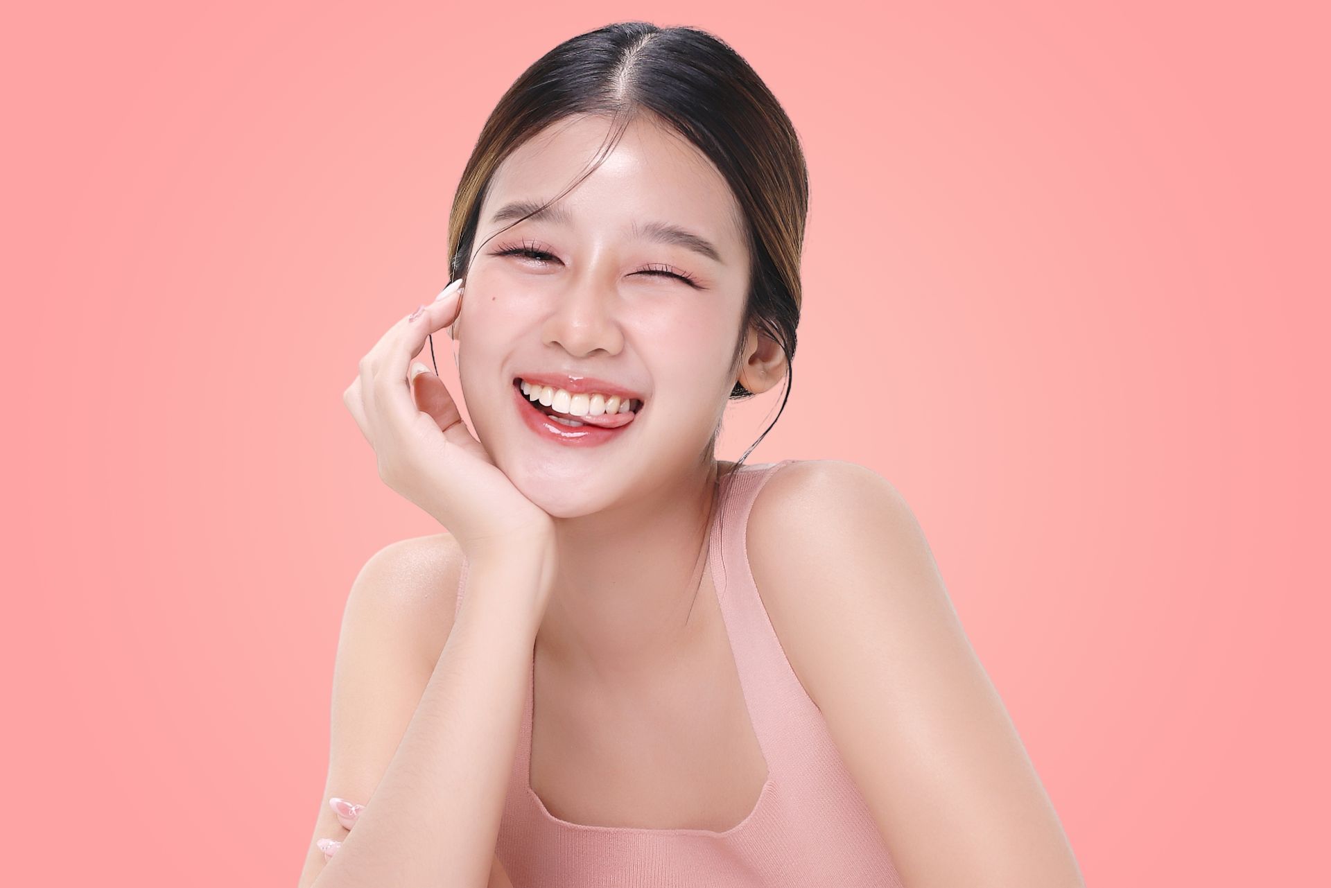 Smiling woman in a pink top posing against a pink background