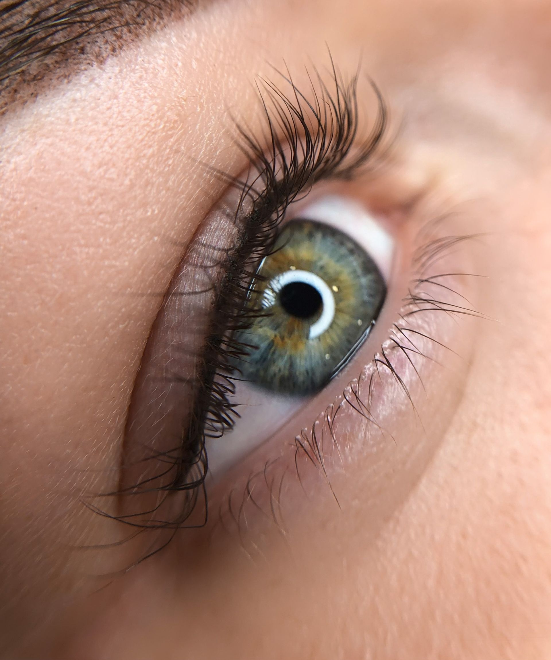 A close up of a woman 's green eye with mascara.