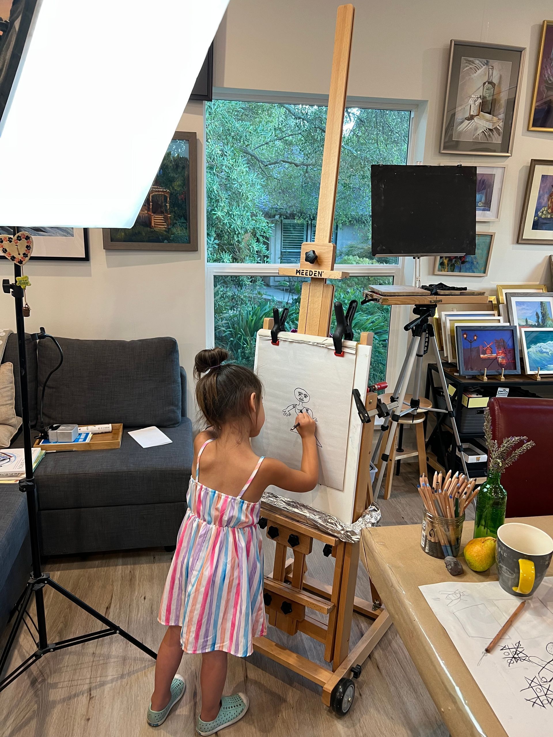 A woman and a girl are sitting at a table in front of a painting.