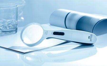 Eine Lupe liegt auf einer Zeitung neben einem Glas Wasser.