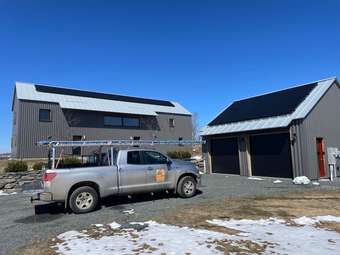 Solar Power VT truck parked in a driveway. The house and garage are showing newly installed solar panels