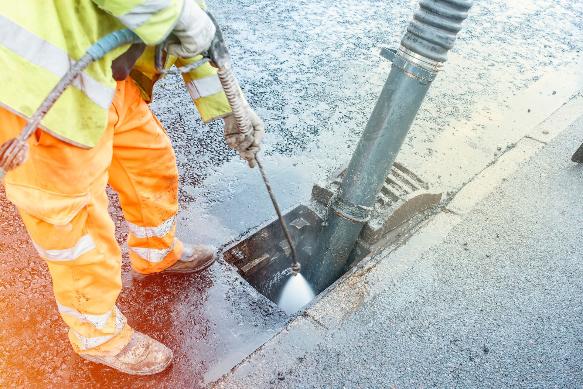 Worker in Orange Safety Gear Using a Jackhammer — Fud's Concreting In Airlie Beach, QLD