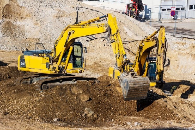 Two Yellow Excavators Are Working on a Construction Site — Fud's Concreting In Collinsville, QLD