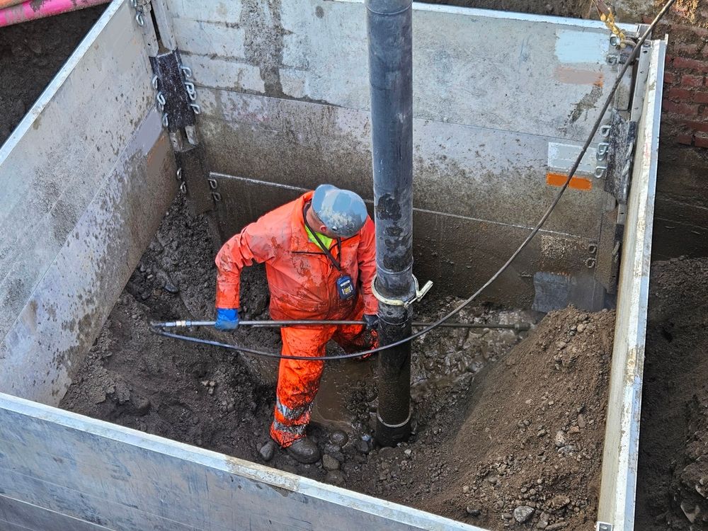 Worker in Orange Safety Gear Stands in a Narrow Trench — Fud's Concreting In Collinsville, QLD