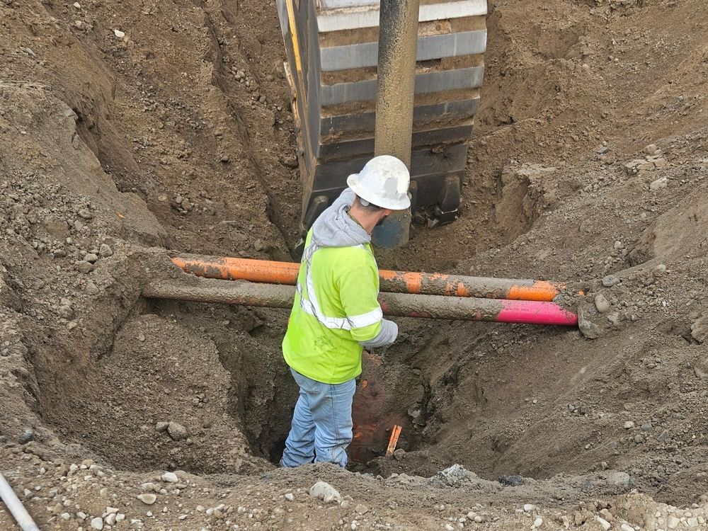 Worker in Hard Hat Stands in a Deep Trench Beside Orange Pipes — Fud's Concreting In Bowen, QLD