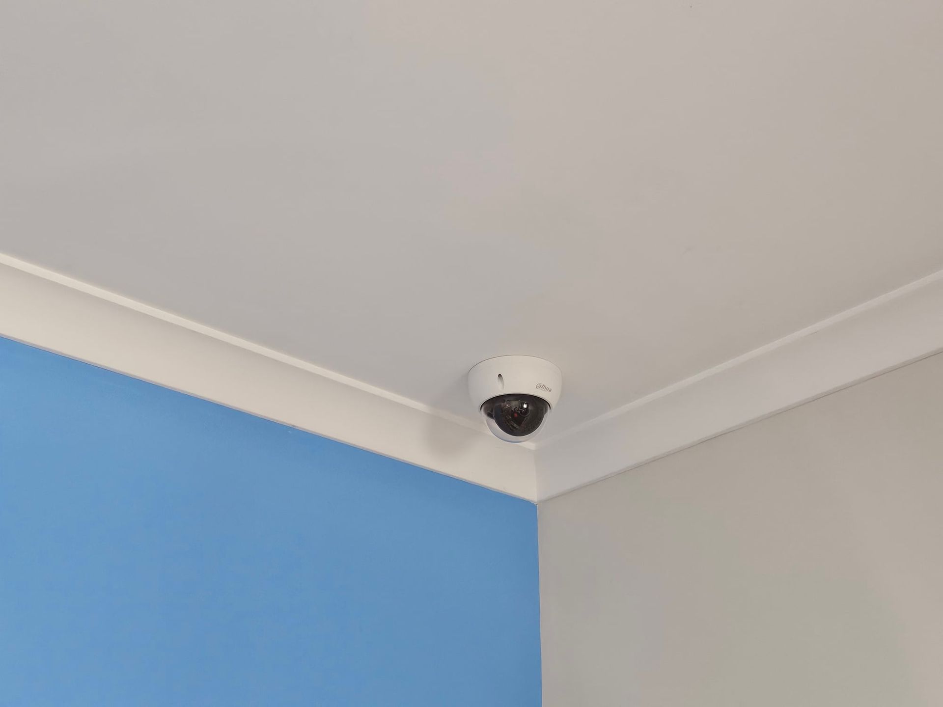 A Security Camera is Mounted on the Ceiling of a Room Next to a Blue Wall — Brisbane Antenna Specialists in Brendale, QLD