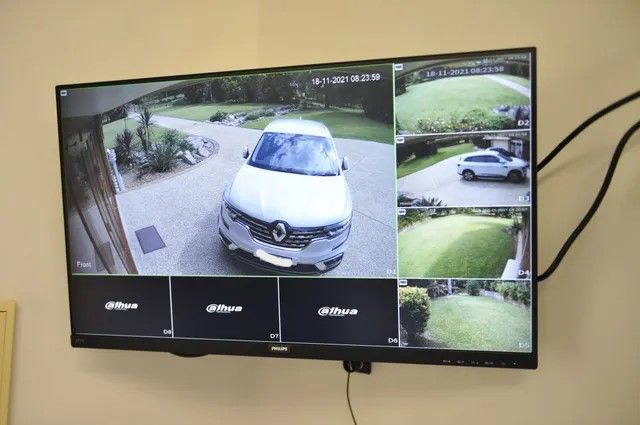 A Large Flat Screen Tv Shows a White Car Parked in a Driveway — Brisbane Antenna Specialists in Brendale, QLD