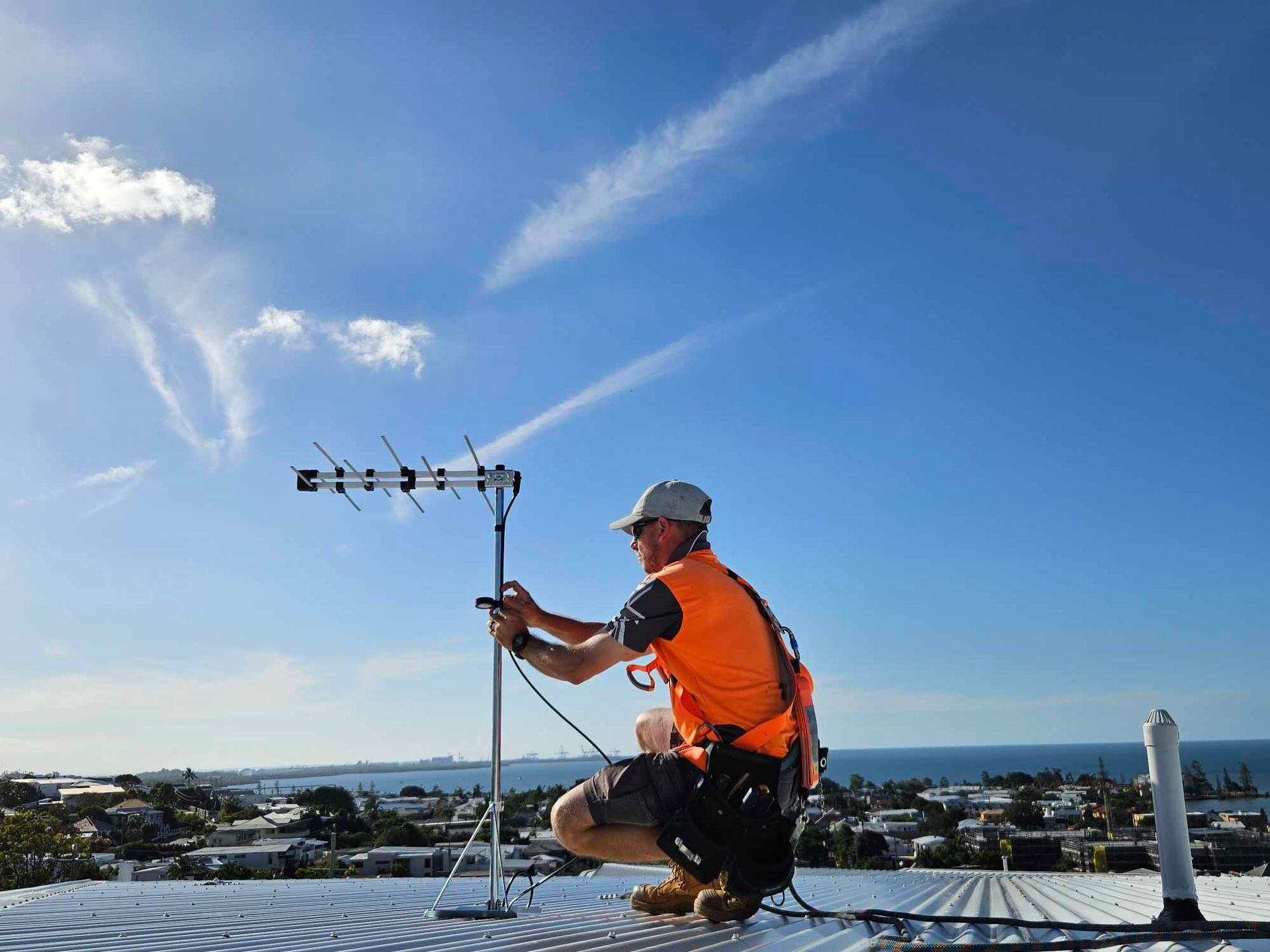 A Man Is Standing In A Crane Bucket On Top Of A Crane — Brisbane Antenna Specialists in Chermside, QLD