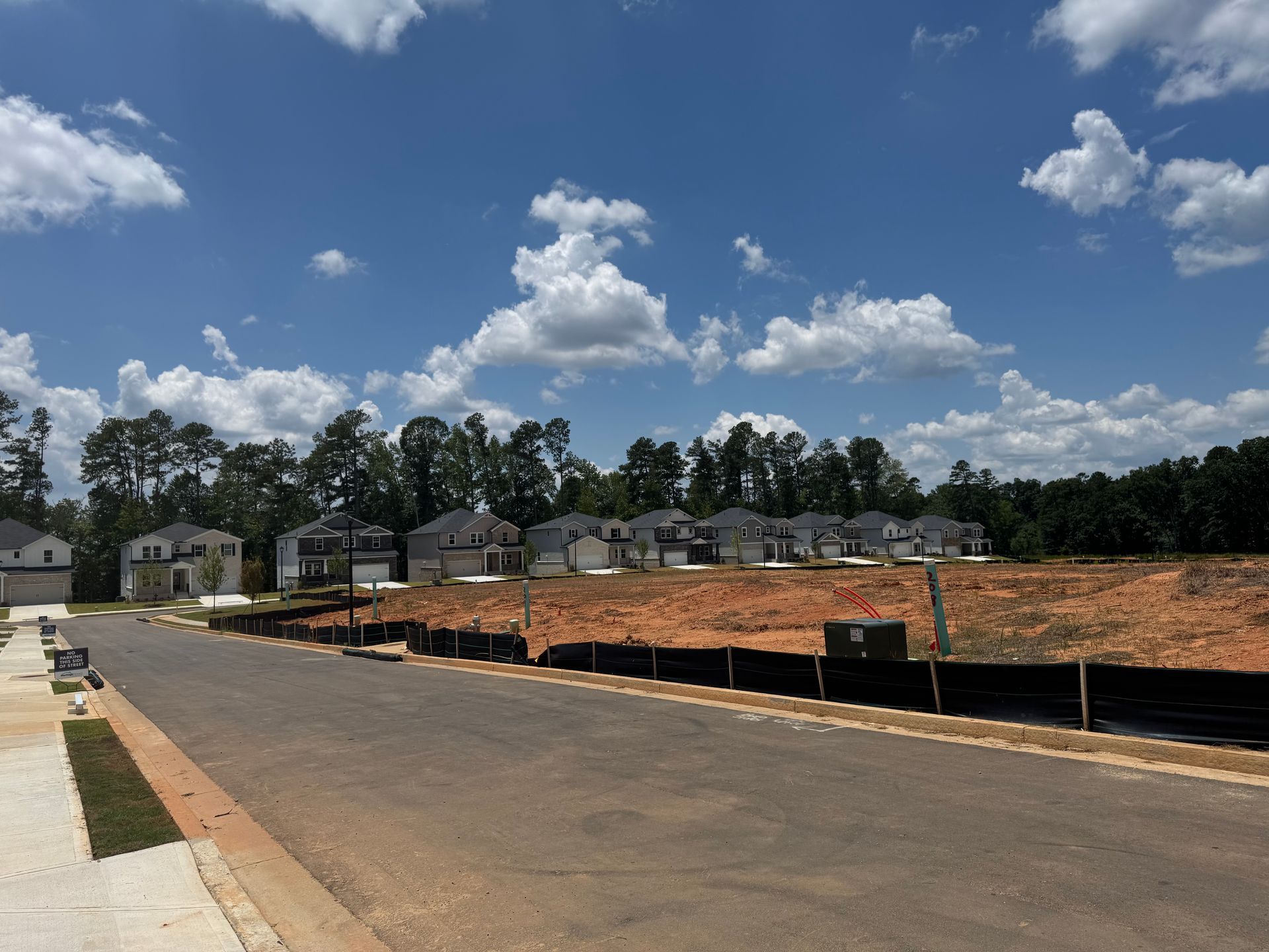 New houses under construction on a sunny day with blue sky and fluffy white clouds.