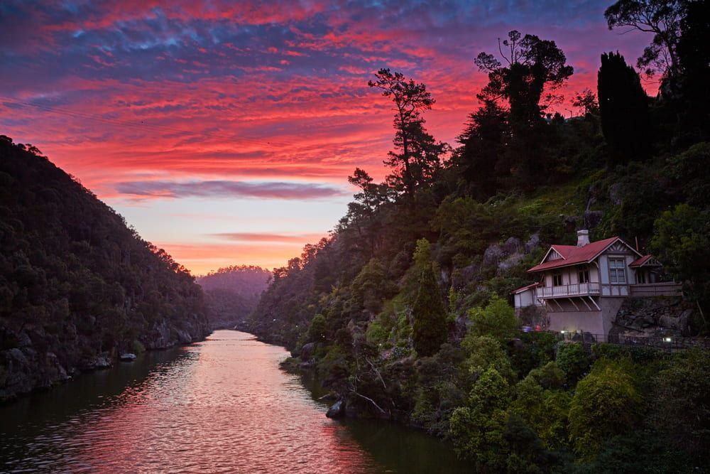 A House Is Sitting on The Shore of A River at Sunset — Arctic Installations in Tasmania, NT