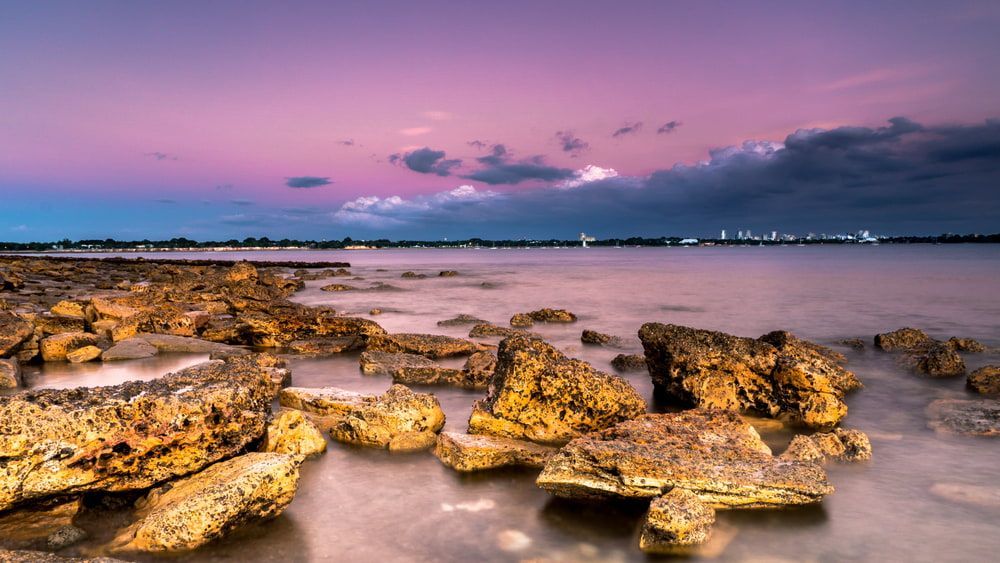 A Sunset Over a Body of Water with Rocks in The Foreground — Arctic Installations in Darwin, NT