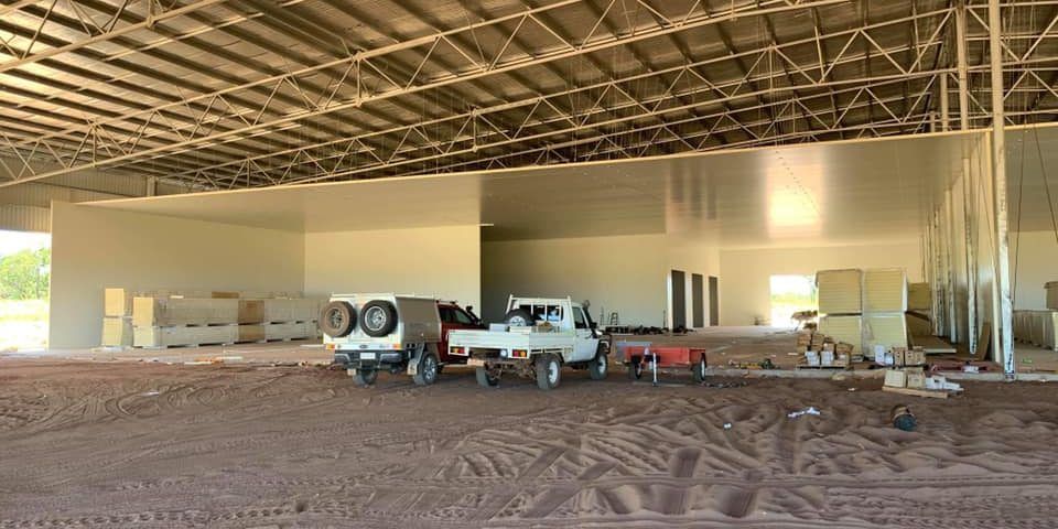 Two White Trucks Are Parked Inside of A Building Under Construction — Arctic Installations in Winnellie, NT