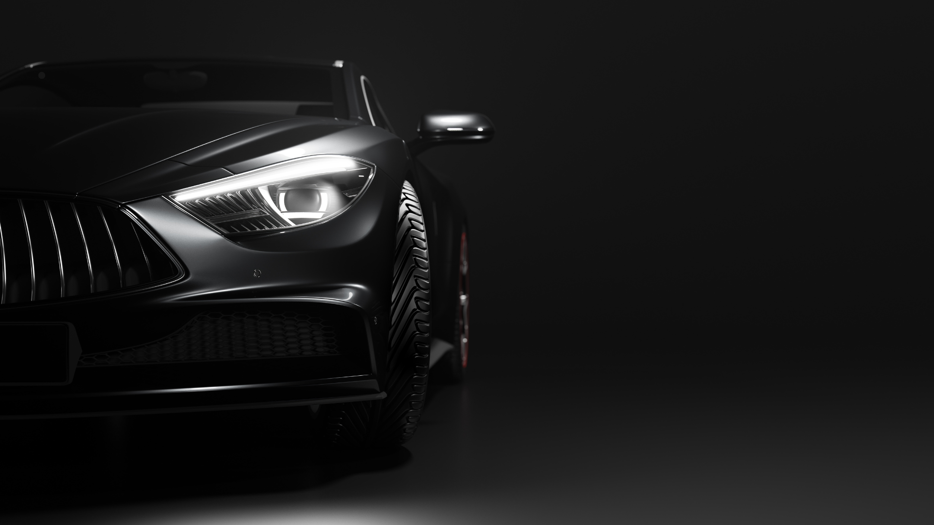 Close-up of the front of a black high-end luxury car, highlighting the sleek headlight, grille, and