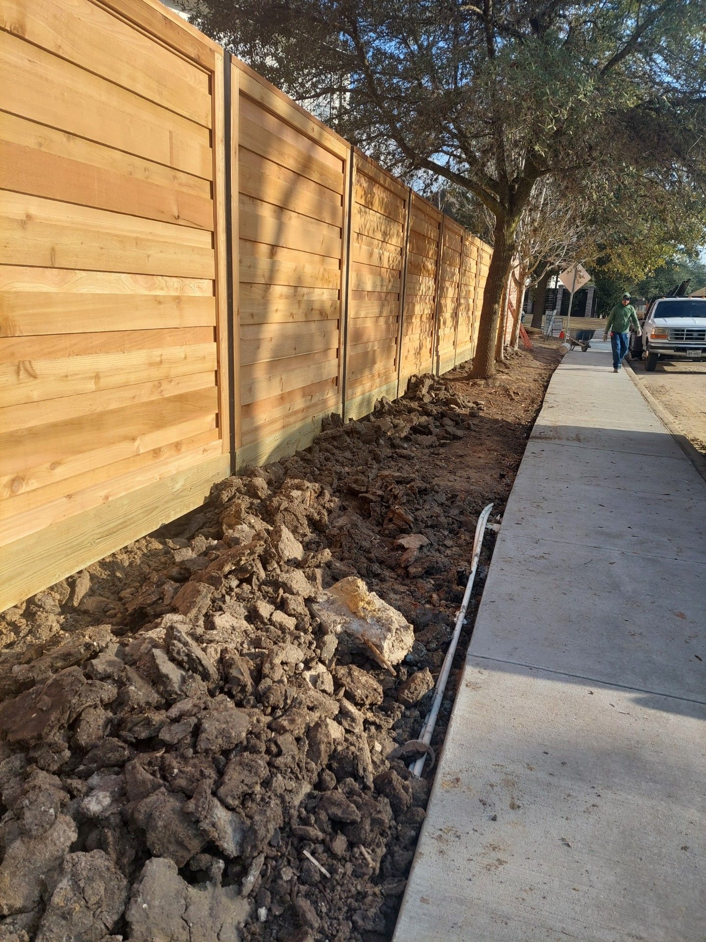 A Wooden Fence Is Being Built Next to A Sidewalk - Houston, TX - Rio Grande Fence Company