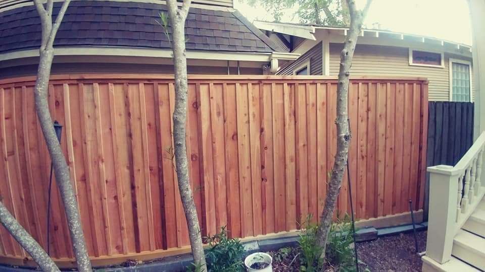 A Wooden Fence Is Surrounded by Trees in Front of A House - Houston, TX - Rio Grande Fence Company