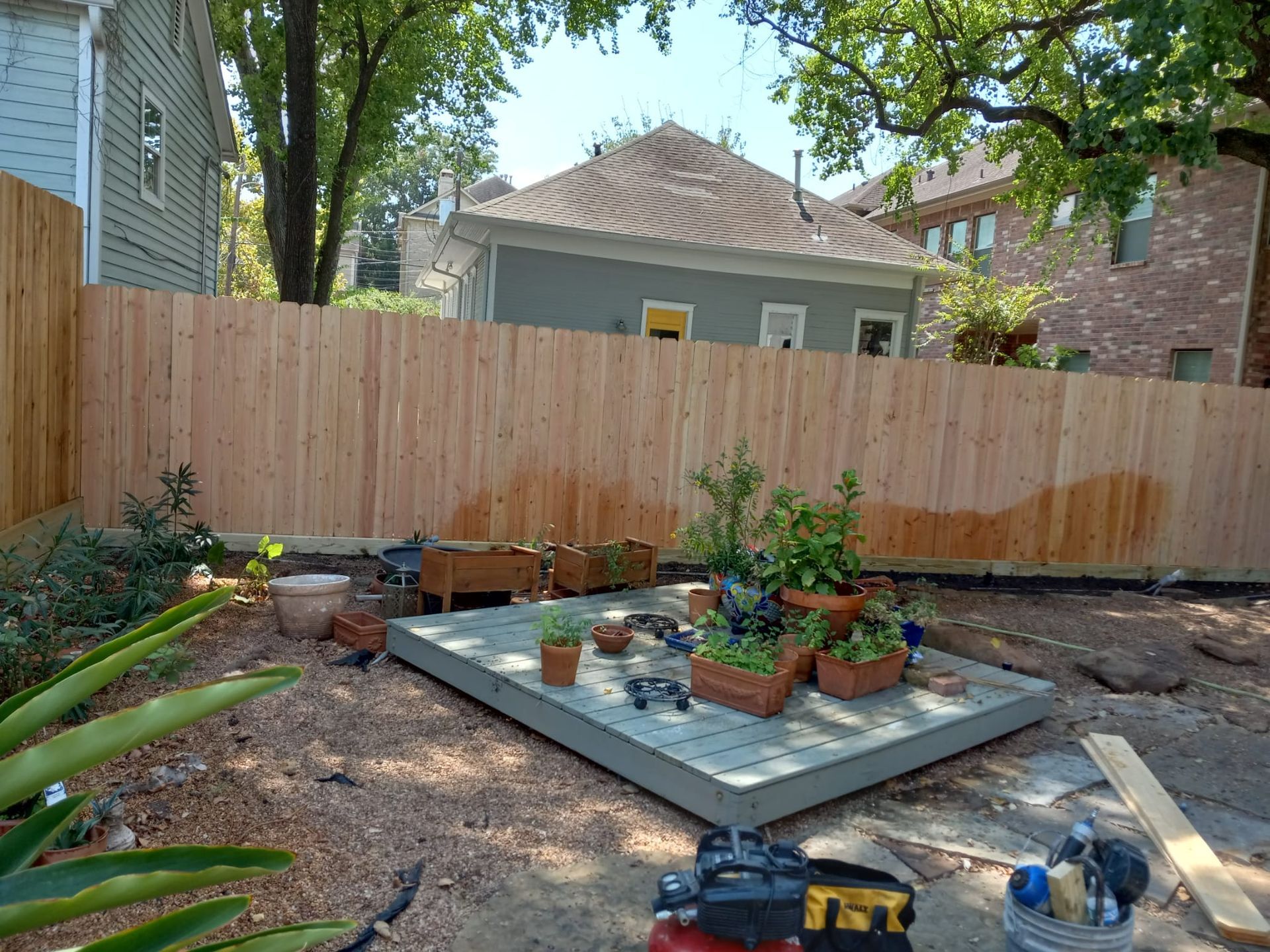 A Wooden Fence Is Surrounding a Garden with Potted Plants - Houston, TX - Rio Grande Fence Company