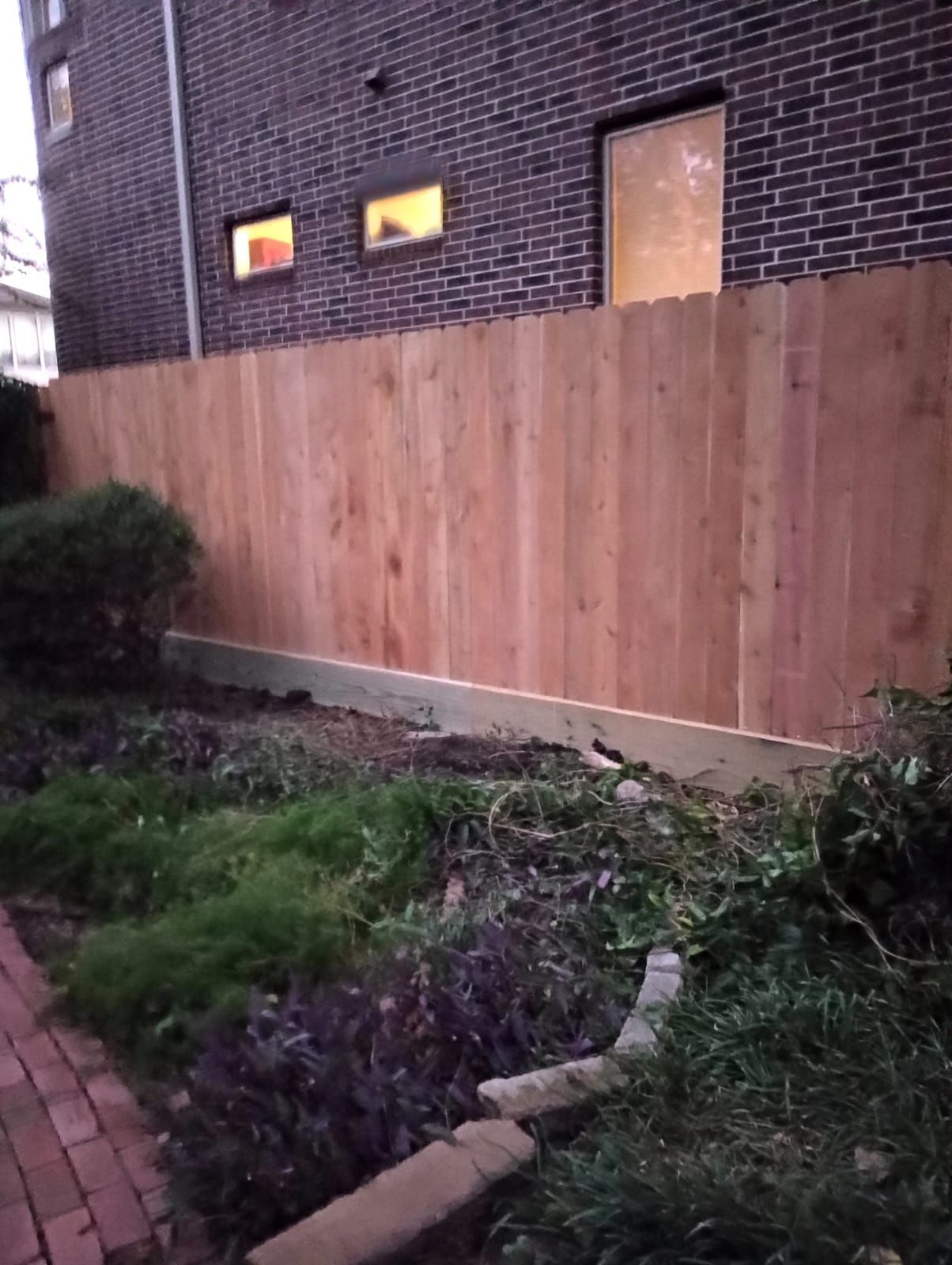 A Wooden Fence Is Sitting in Front of A Brick Building - Houston, TX - Rio Grande Fence Company