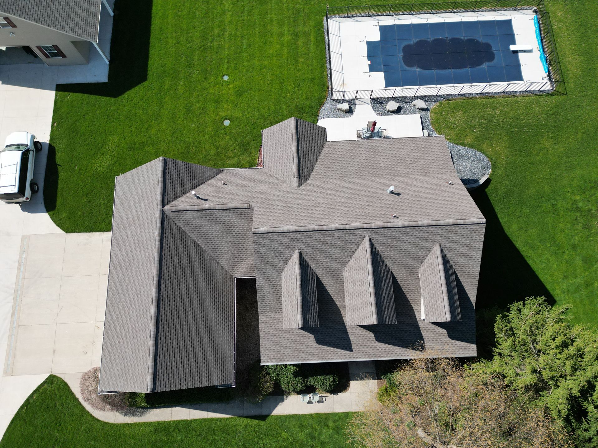 aerial photo  of house taken by a drone with a more advanced roof installed by top shelf construction and consulting. a pool can be seen in the backyard