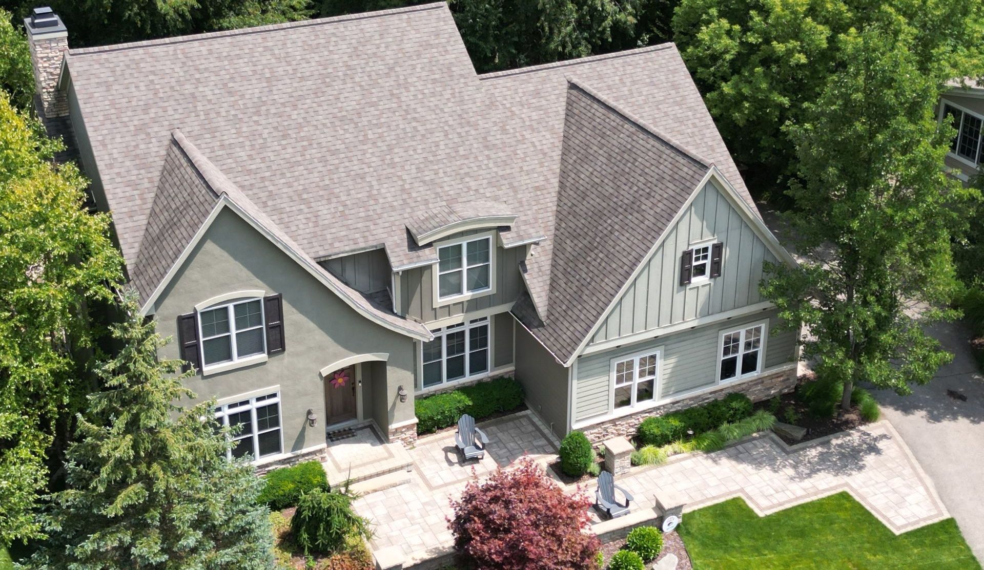 aerial corner shot by a drone of a pristine house with a roof done by top shelf construction and consulting. the front of the house has a unique slope like a ramp