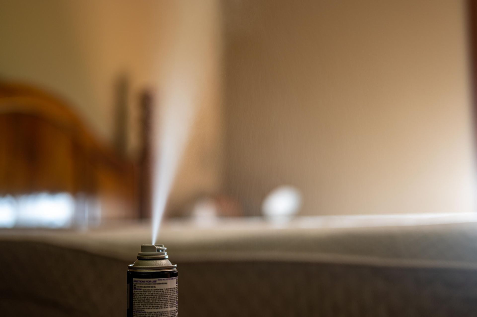 A spray bottle is spraying air freshener in a bedroom.